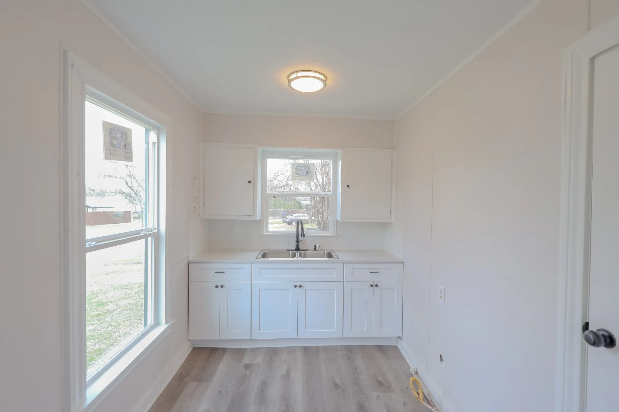 Bright and airy bathroom featuring a white cabinetry vanity with dual sink configuration, polished countertop, and chrome fixtures