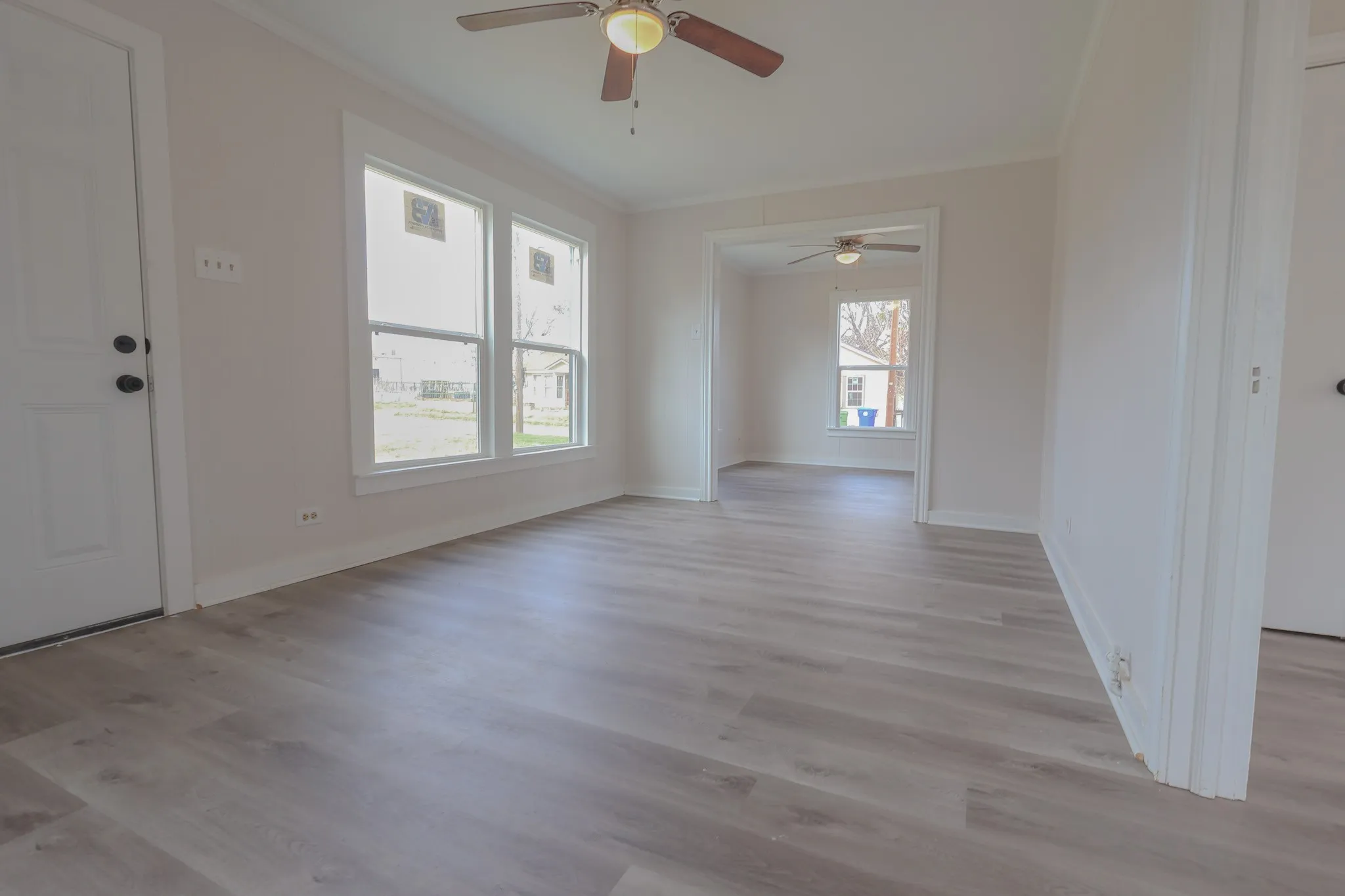 Wood-finish flooring throughout, multiple windows, overhead ceiling fan, and white trim