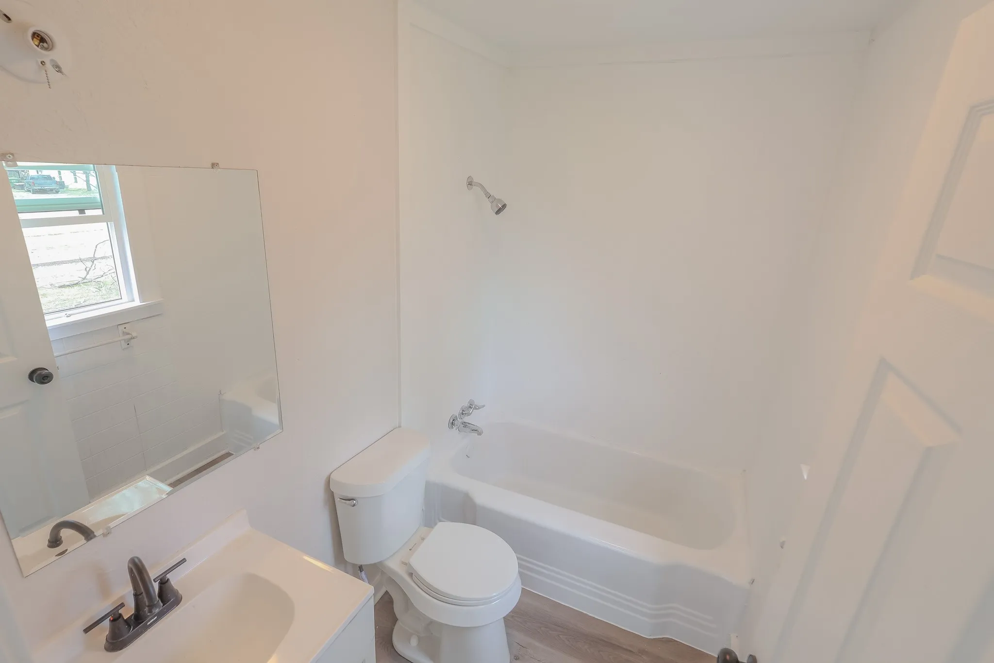 White bathroom vanity with integrated sink, contemporary matte black faucet, and a wall-mounted mirror