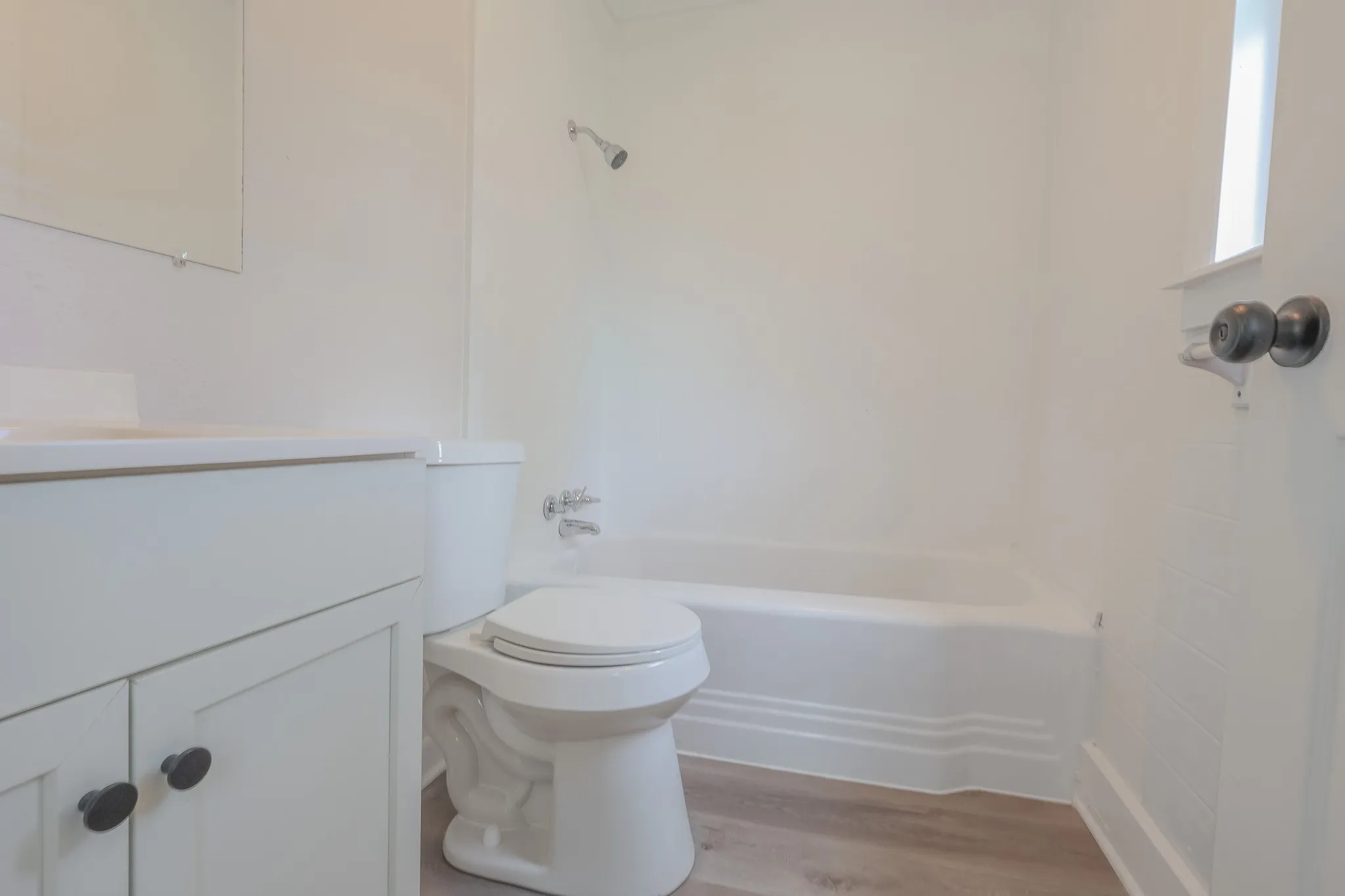 Bathroom featuring a built-in tub and shower combination, vanity with cabinet storage, and wood-finish flooring