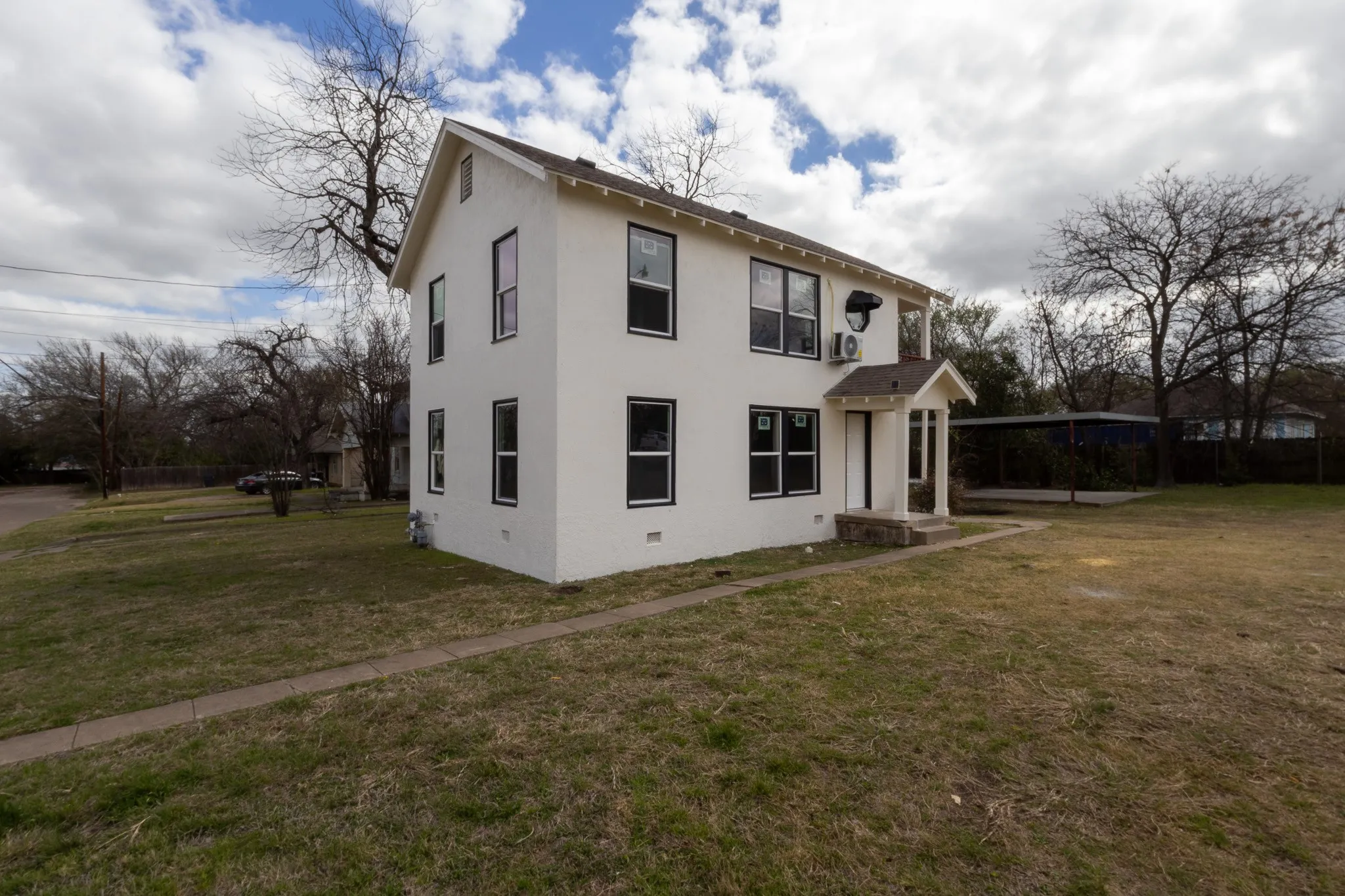 Two-story exterior with white stucco finish and black-framed windows