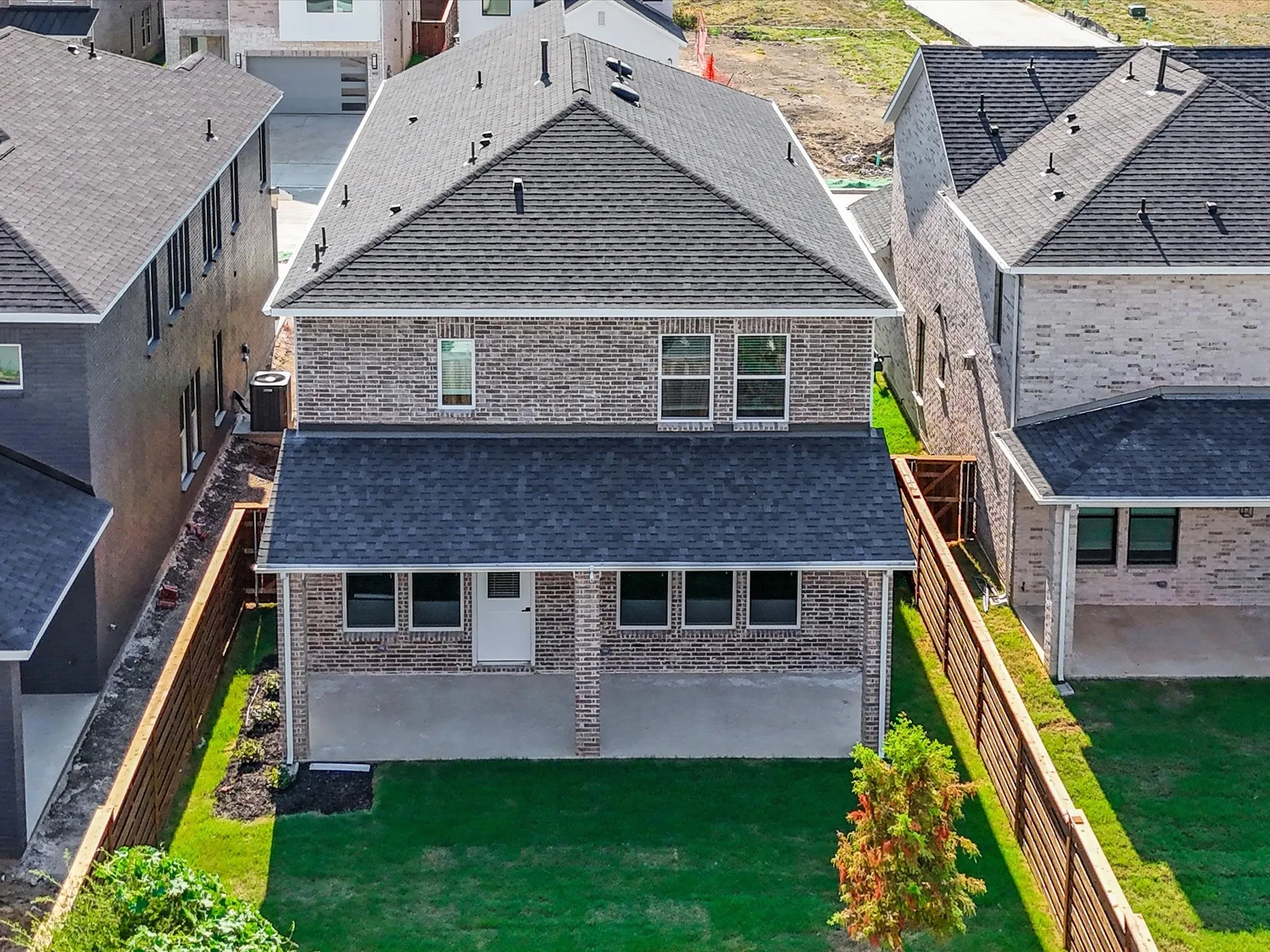 Rear view of house featuring roof with shingles, brick siding, and a fenced backyard