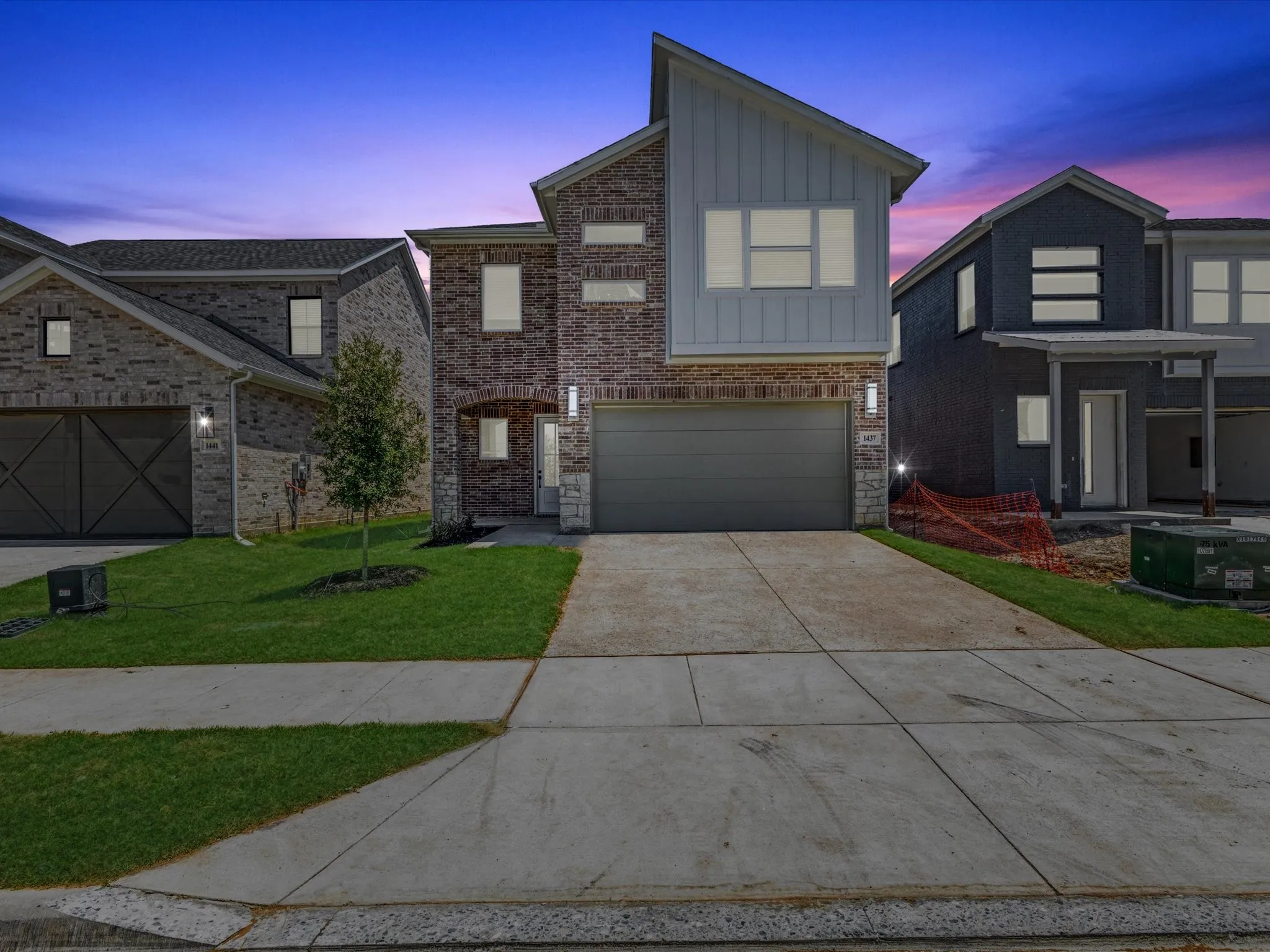 View of front of home with board and batten siding, driveway, a yard, and an attached garage