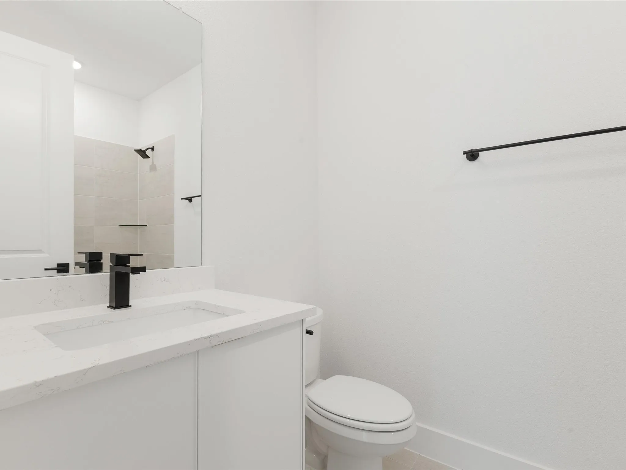 Ensuite bathroom featuring vanity, light tile patterned floors, and a tile shower