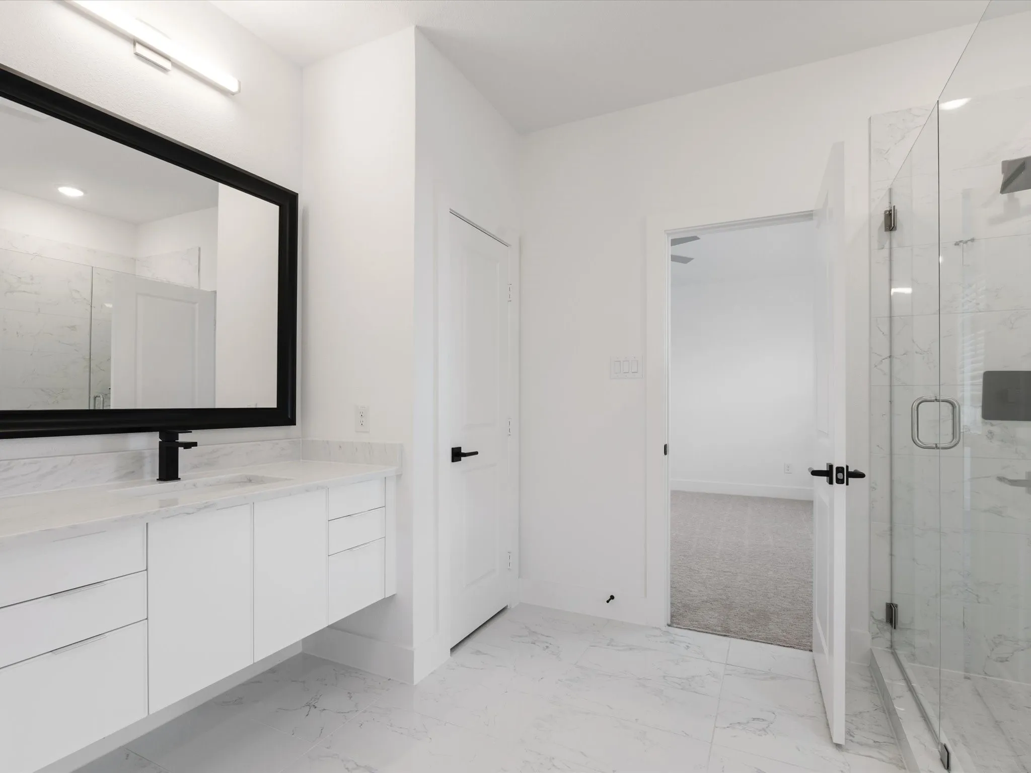 Primary Bathroom featuring vanity, a marble finish shower, and light marble finish floors