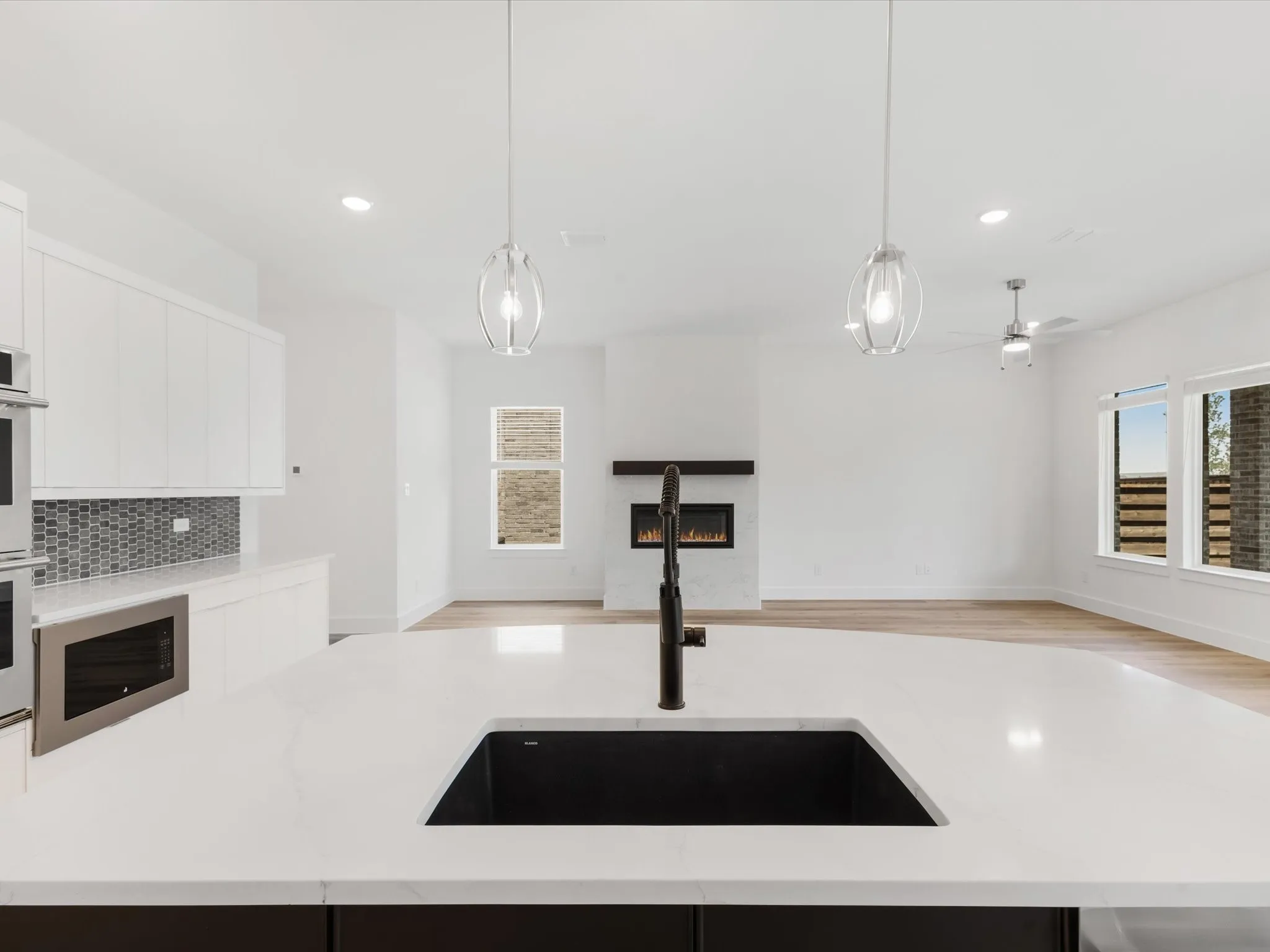 Kitchen with decorative light fixtures, open floor plan, light stone counters, and recessed lighting