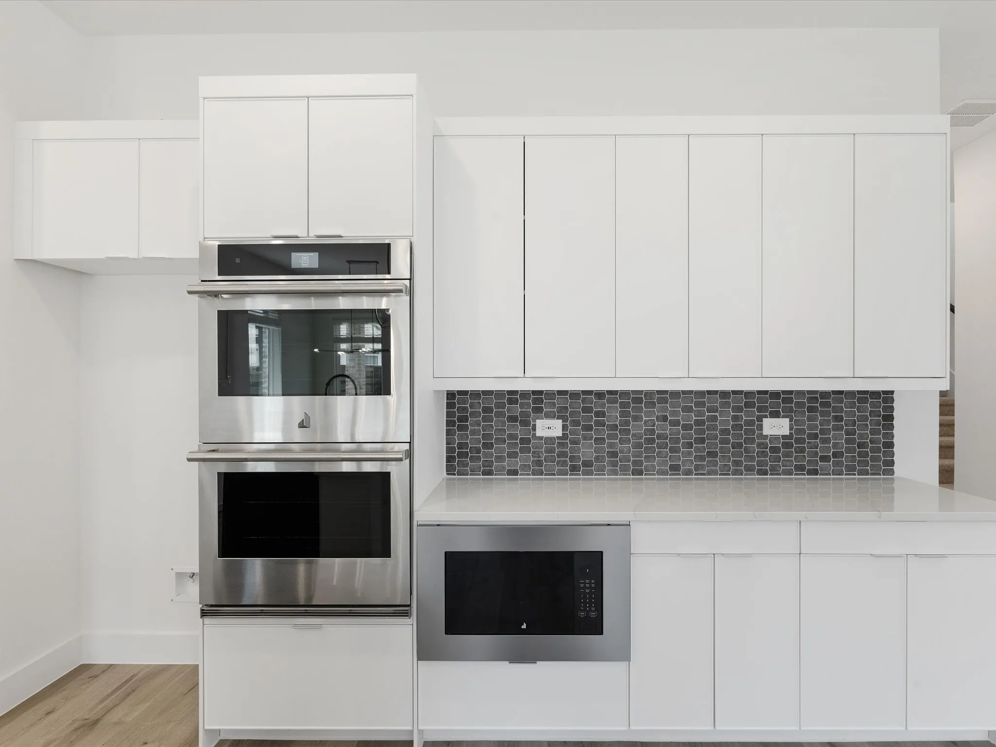 Kitchen with stainless steel appliances, white cabinets, modern cabinets, light stone counters, and light wood finished floors