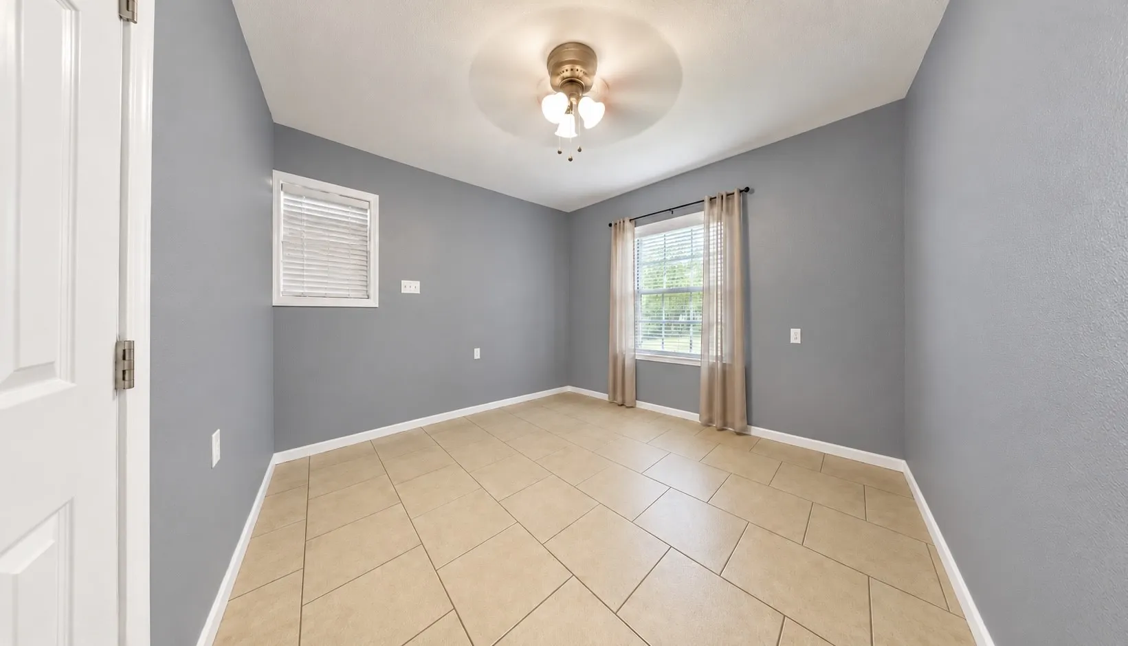 Neutral wall paint, ceiling fan with integrated lighting, tiled flooring, and window treatments