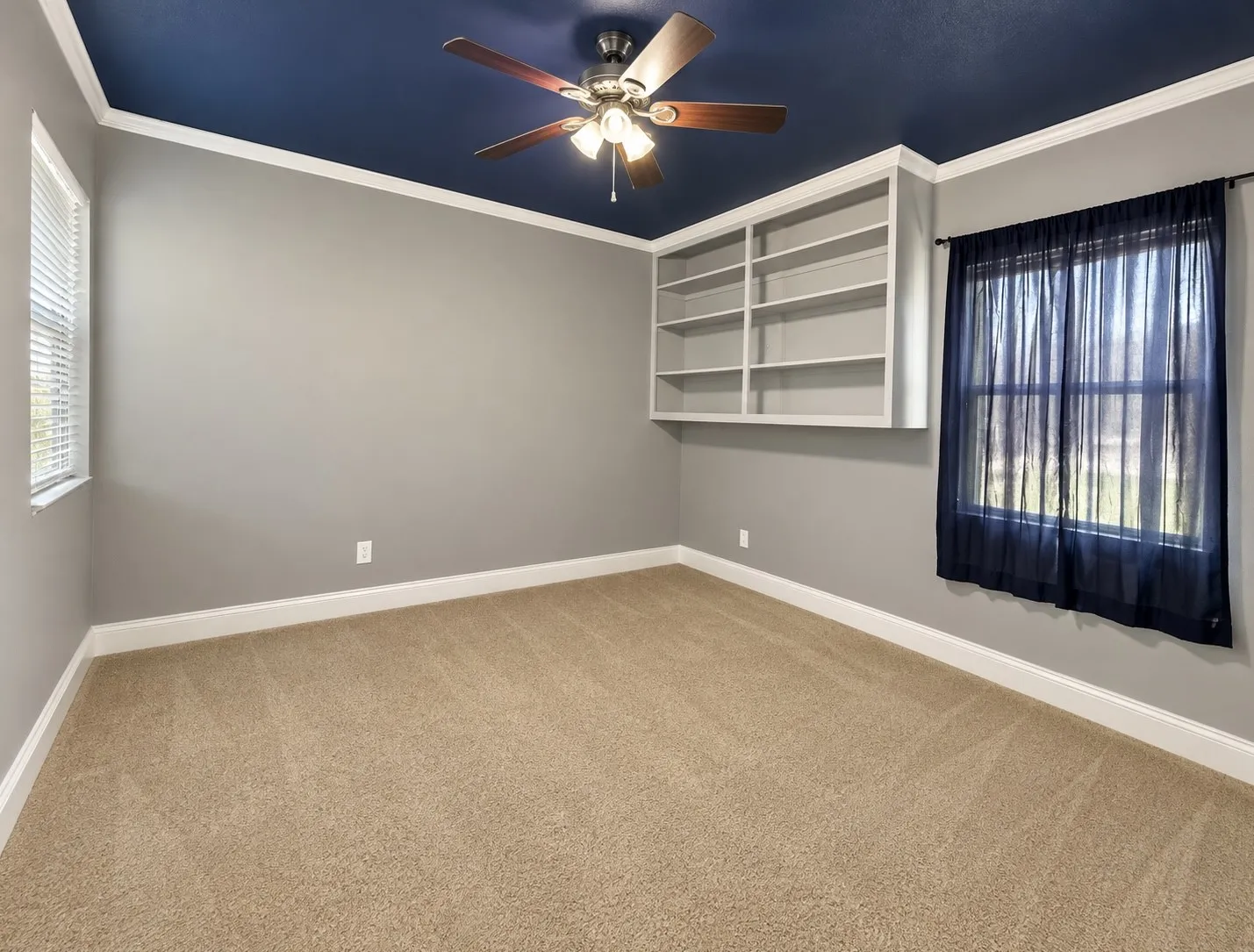 Built-in shelving, crown molding, and a ceiling fan with light fixture