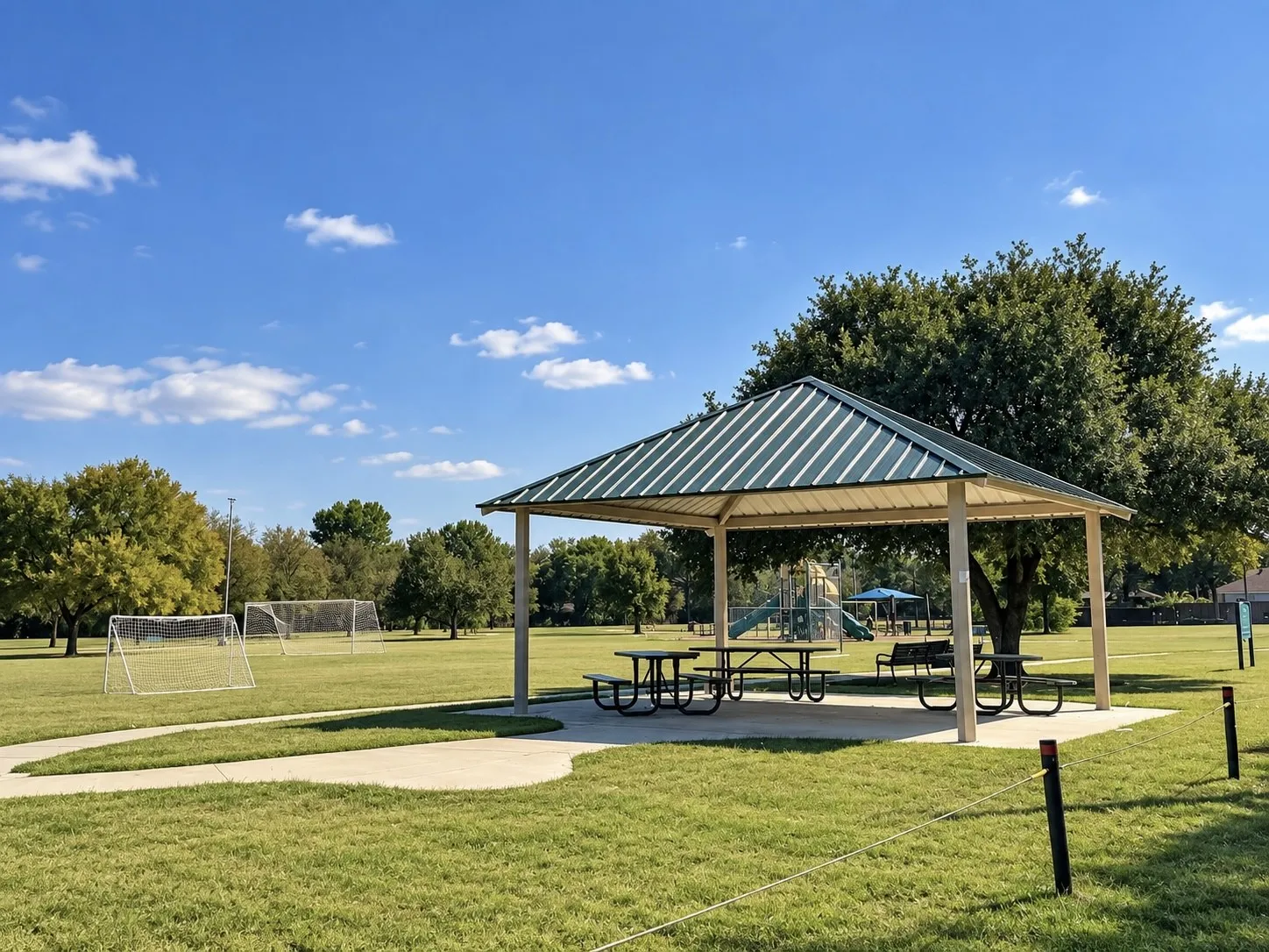 Outdoor pavilion with a metal roof, concrete pad, and picnic tables