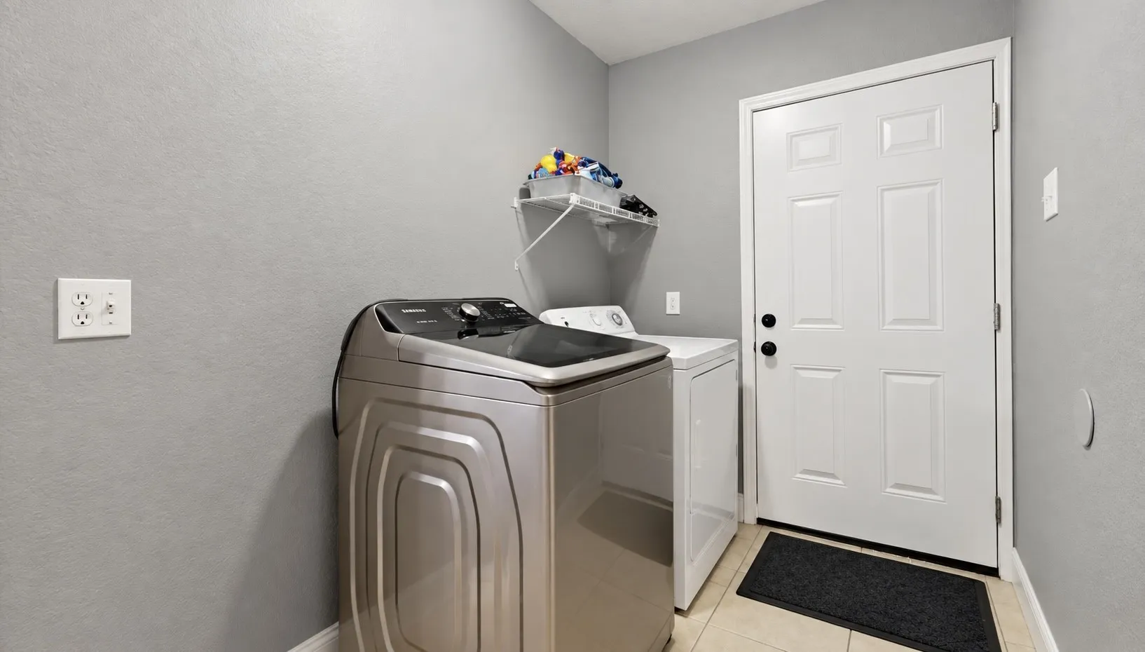 Laundry area featuring tile flooring, white walls, and a built-in wall shelf