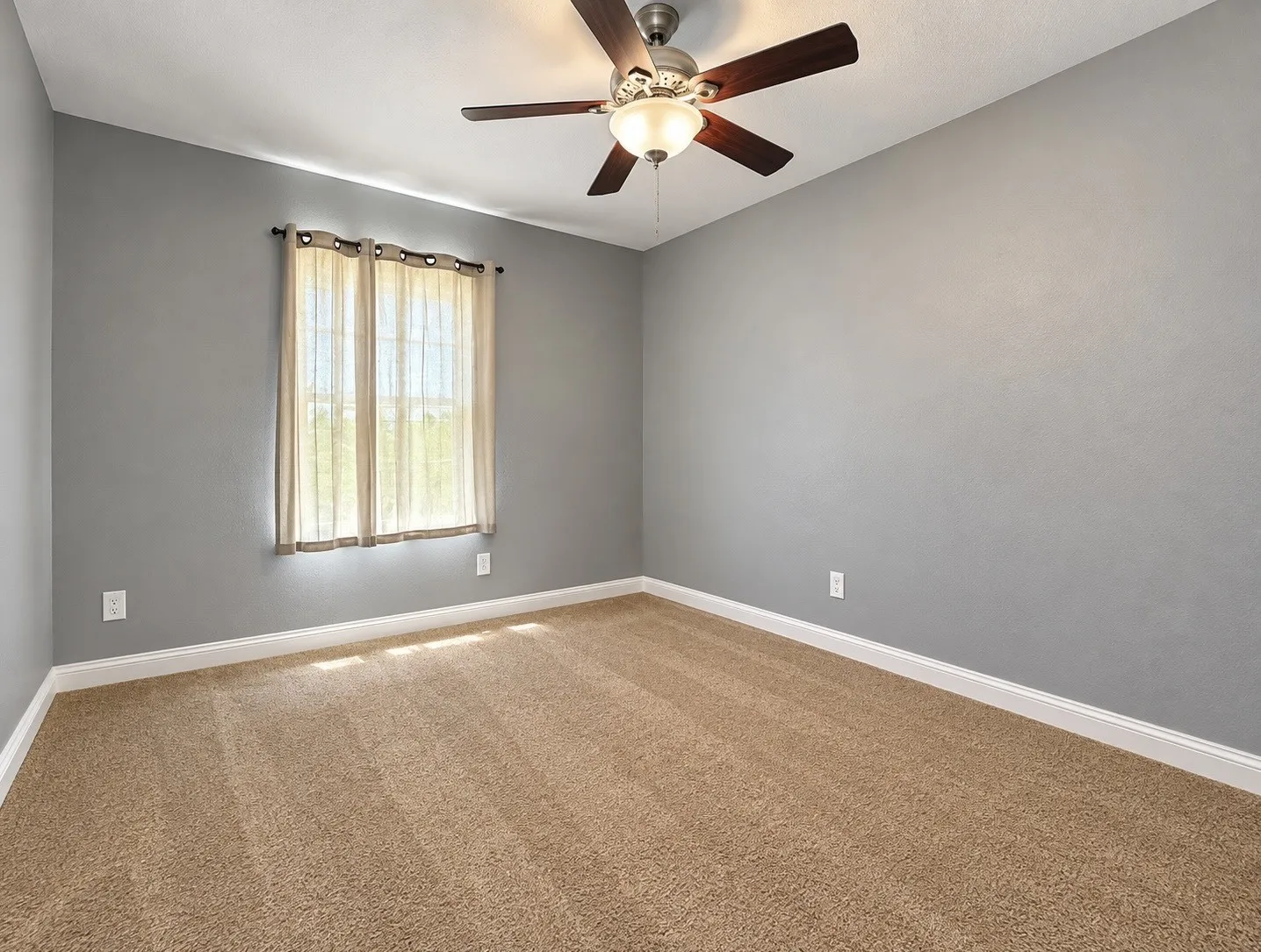 Carpeted room with a ceiling fan and light fixture, featuring a window with sheer curtains