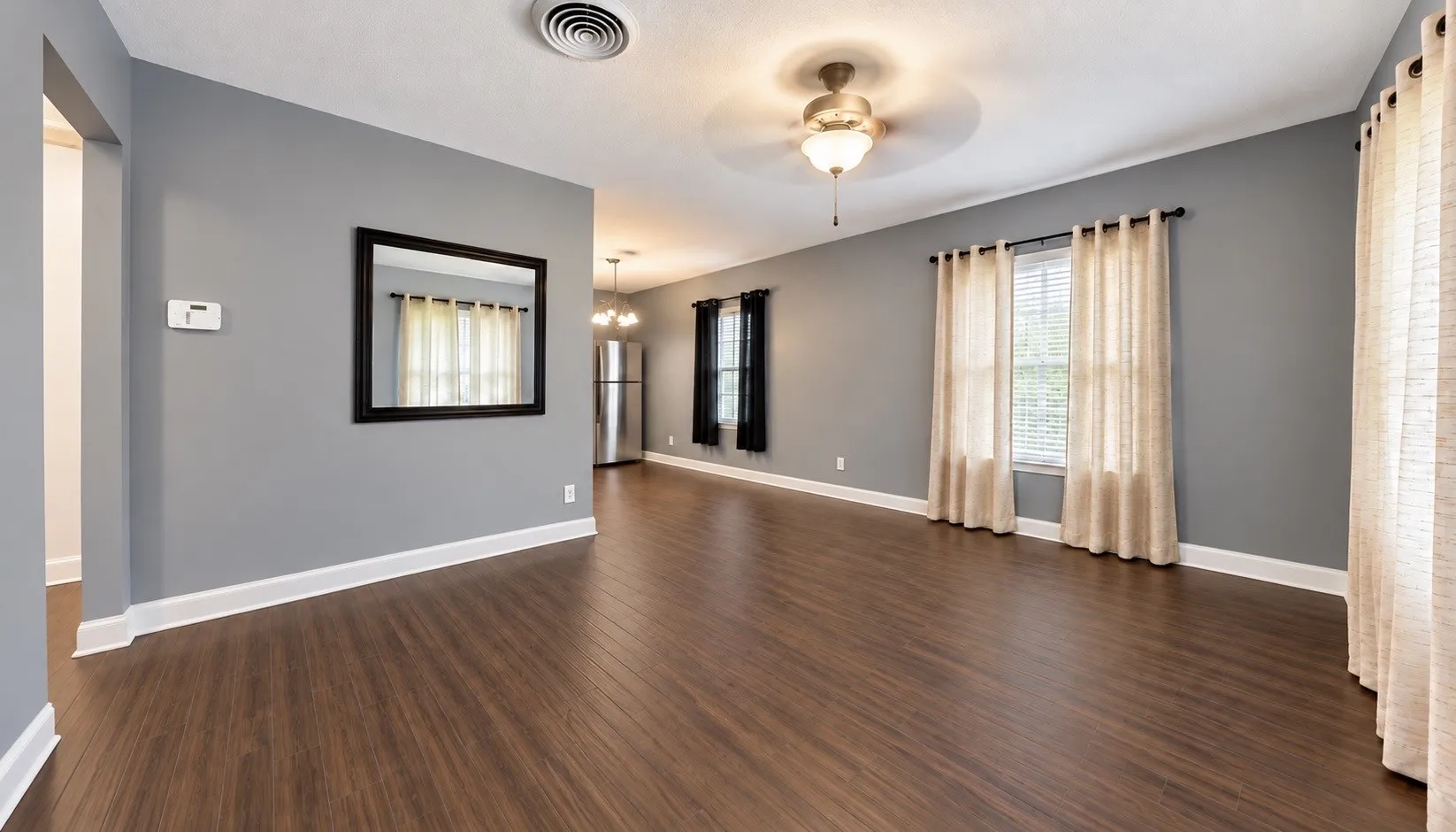 Wood-finish flooring, ceiling fan with integrated lighting, multiple windows, and crown molding