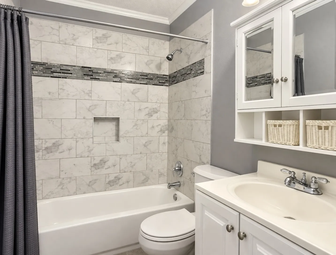 Bathtub featuring subway tile surround with decorative accent band and recessed niche