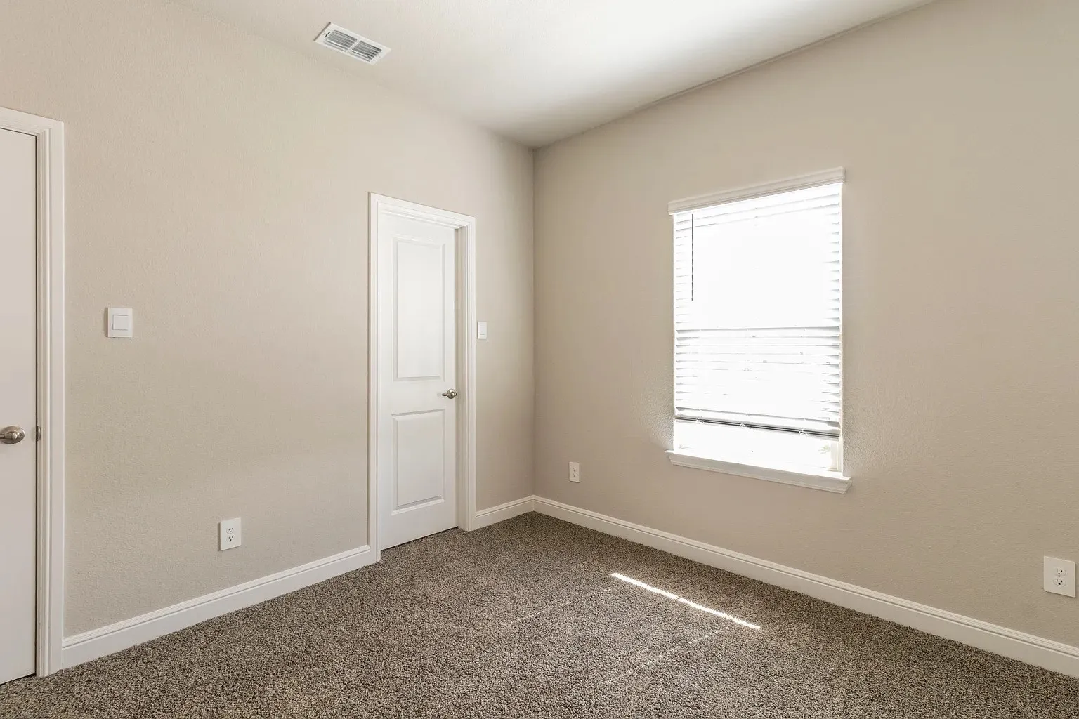 Wall-to-wall carpeting, neutral wall finishes, white trim, white paneled doors, and a window with blinds