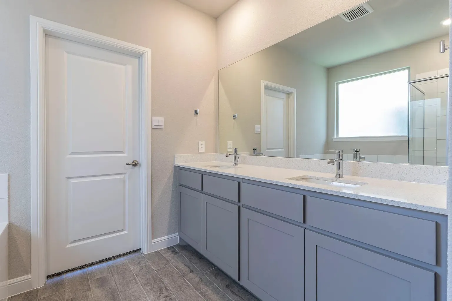 Double vanity with gray shaker cabinetry, dual undermount sinks, and light-toned countertops