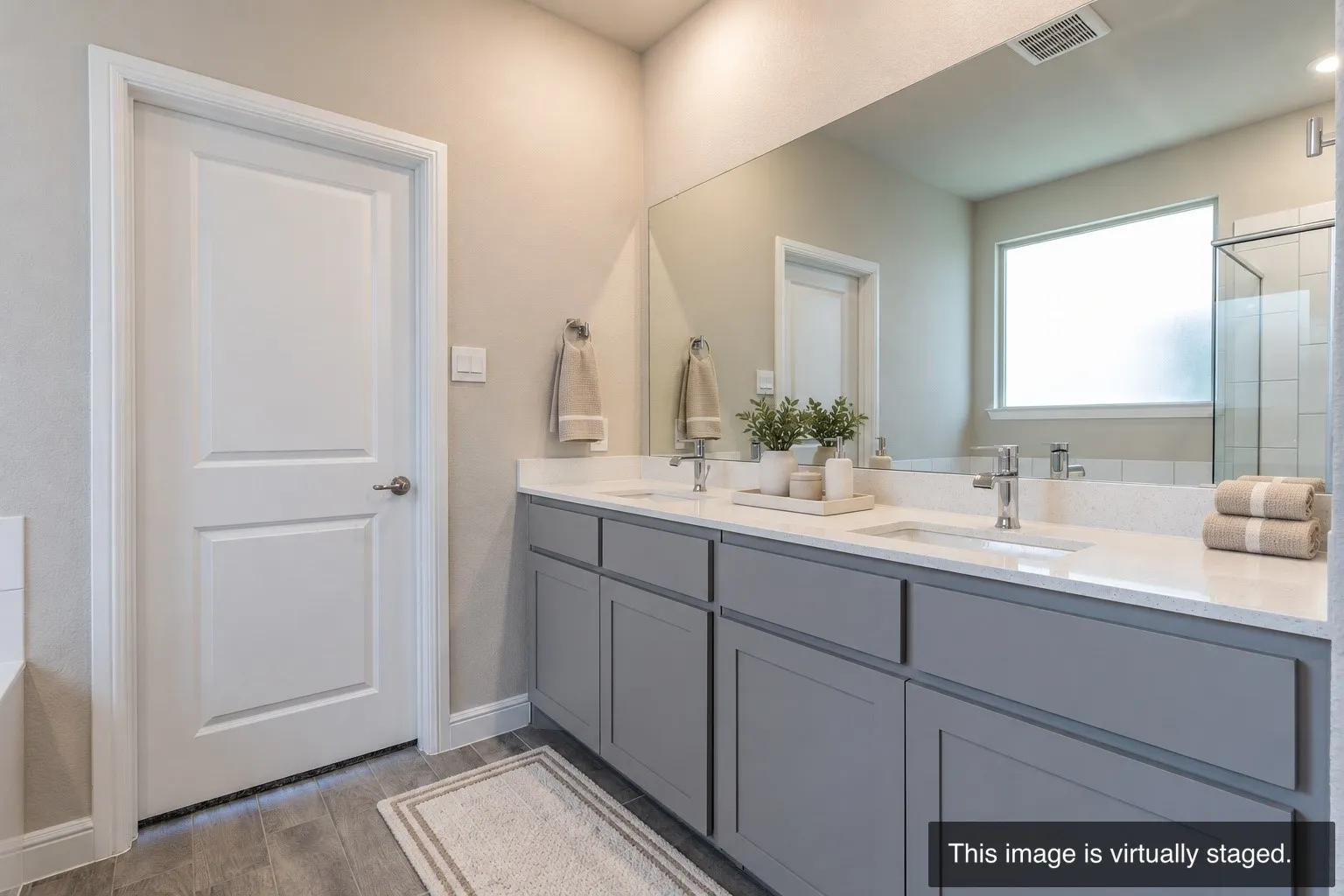 Dual vanity with under-mount sinks, wood-finish flooring, full-width mirror, and a frosted glass window