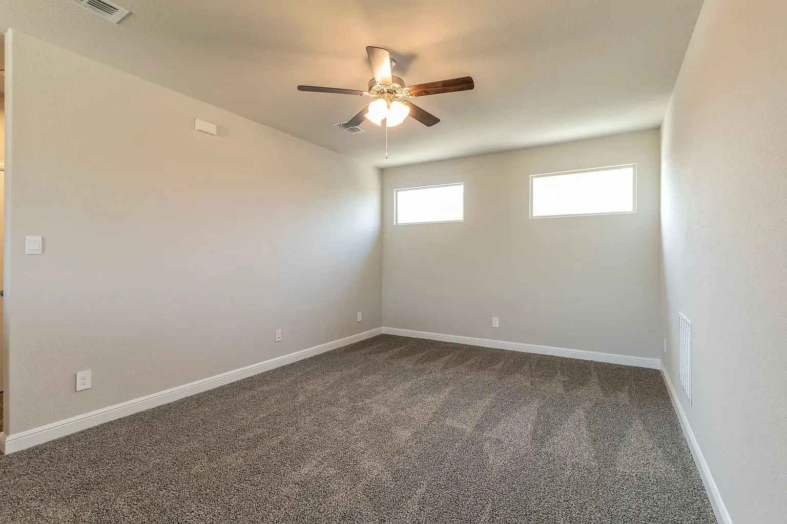 Spacious room featuring neutral carpeting, a ceiling fan with integrated lighting, and high-set windows
