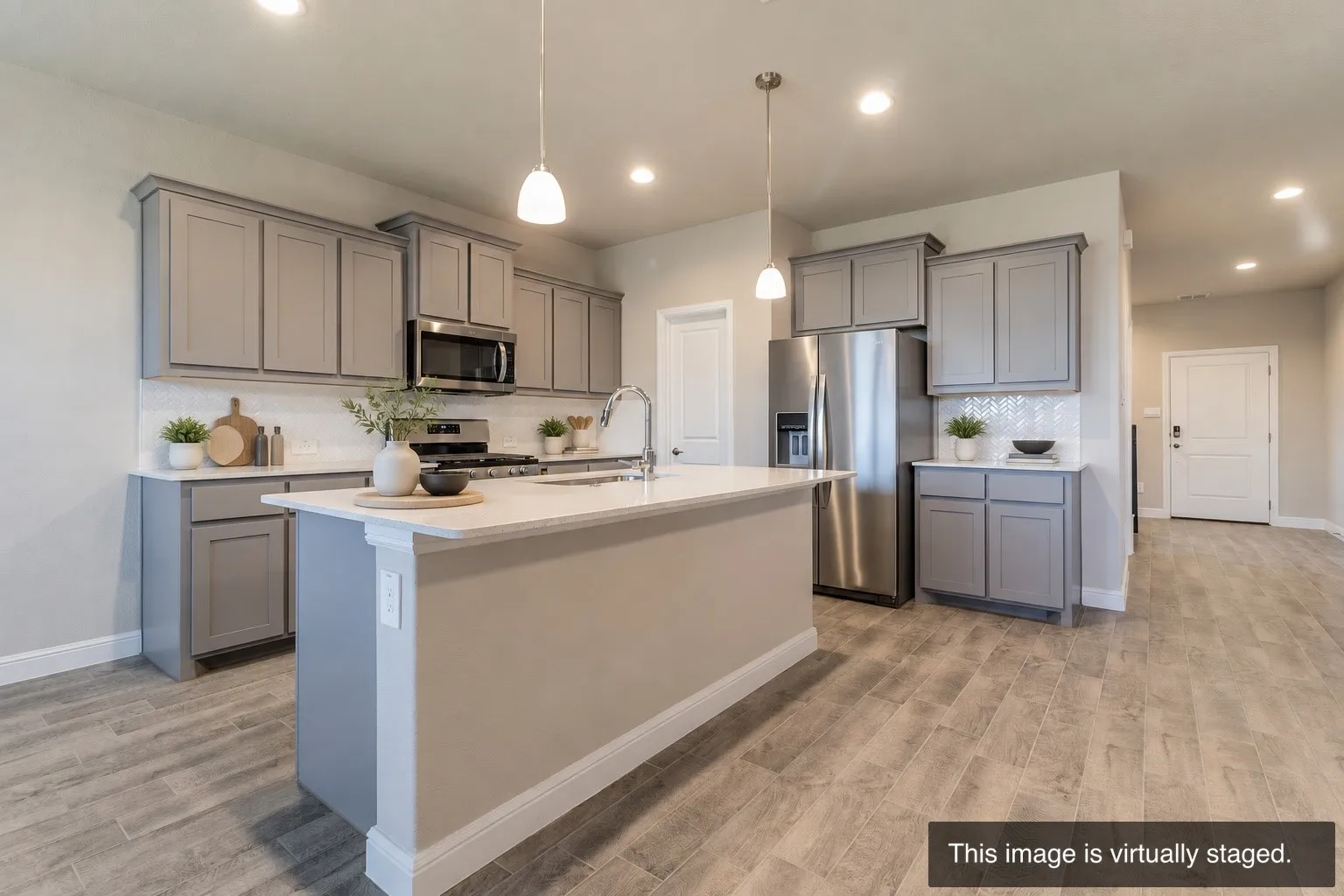 Kitchen featuring an island with a light-colored countertop, gray cabinetry, stainless steel appliances, and wood-finish flooring