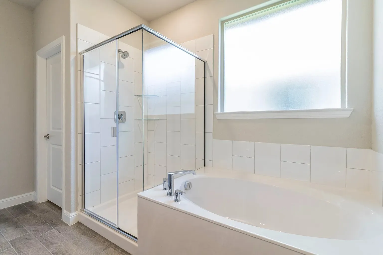 Walk-in glass shower with tile surround, built-in bathtub, and a frosted privacy window