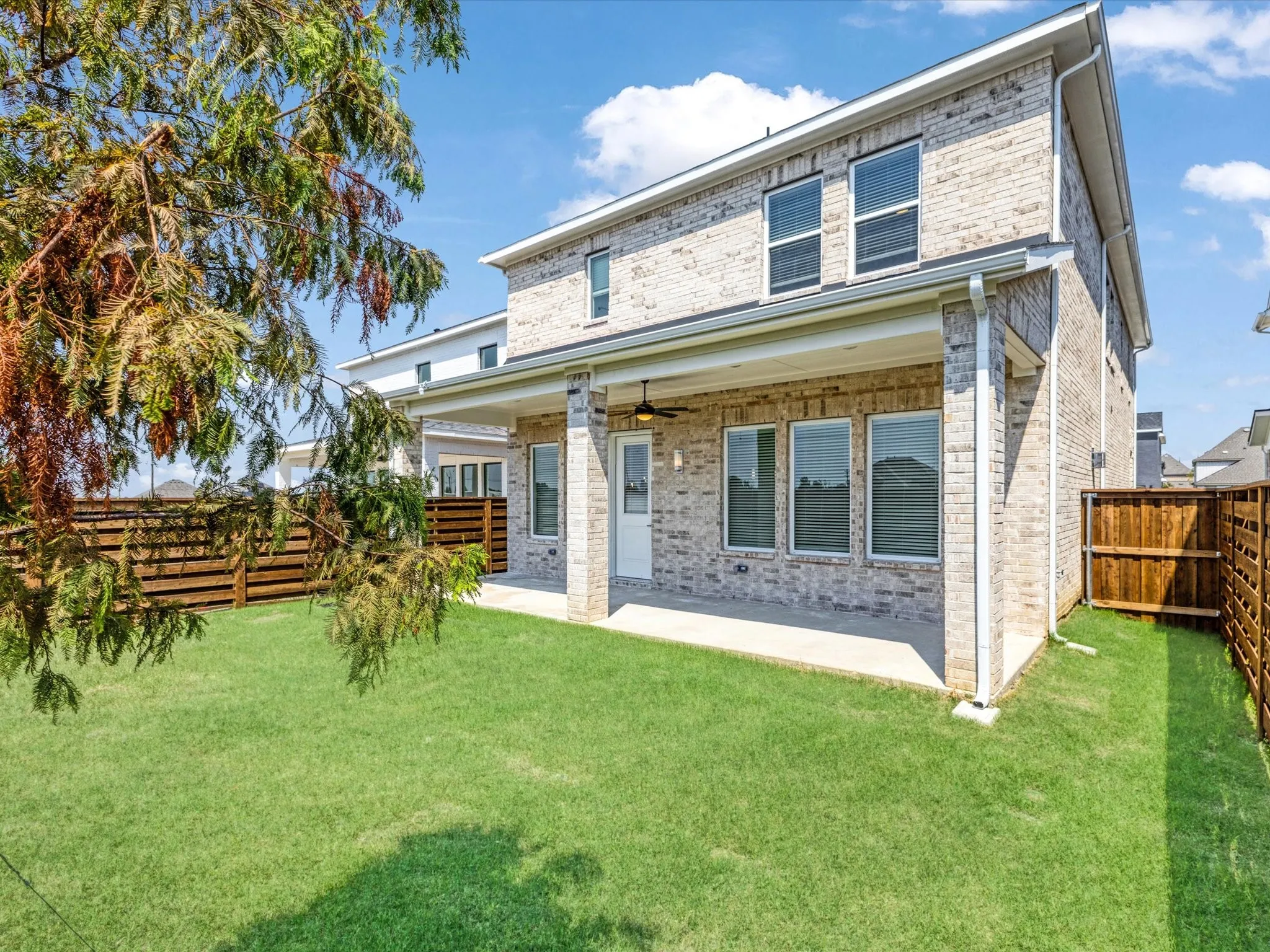 Back of house featuring a patio area, brick siding, a fenced backyard, and a ceiling fan