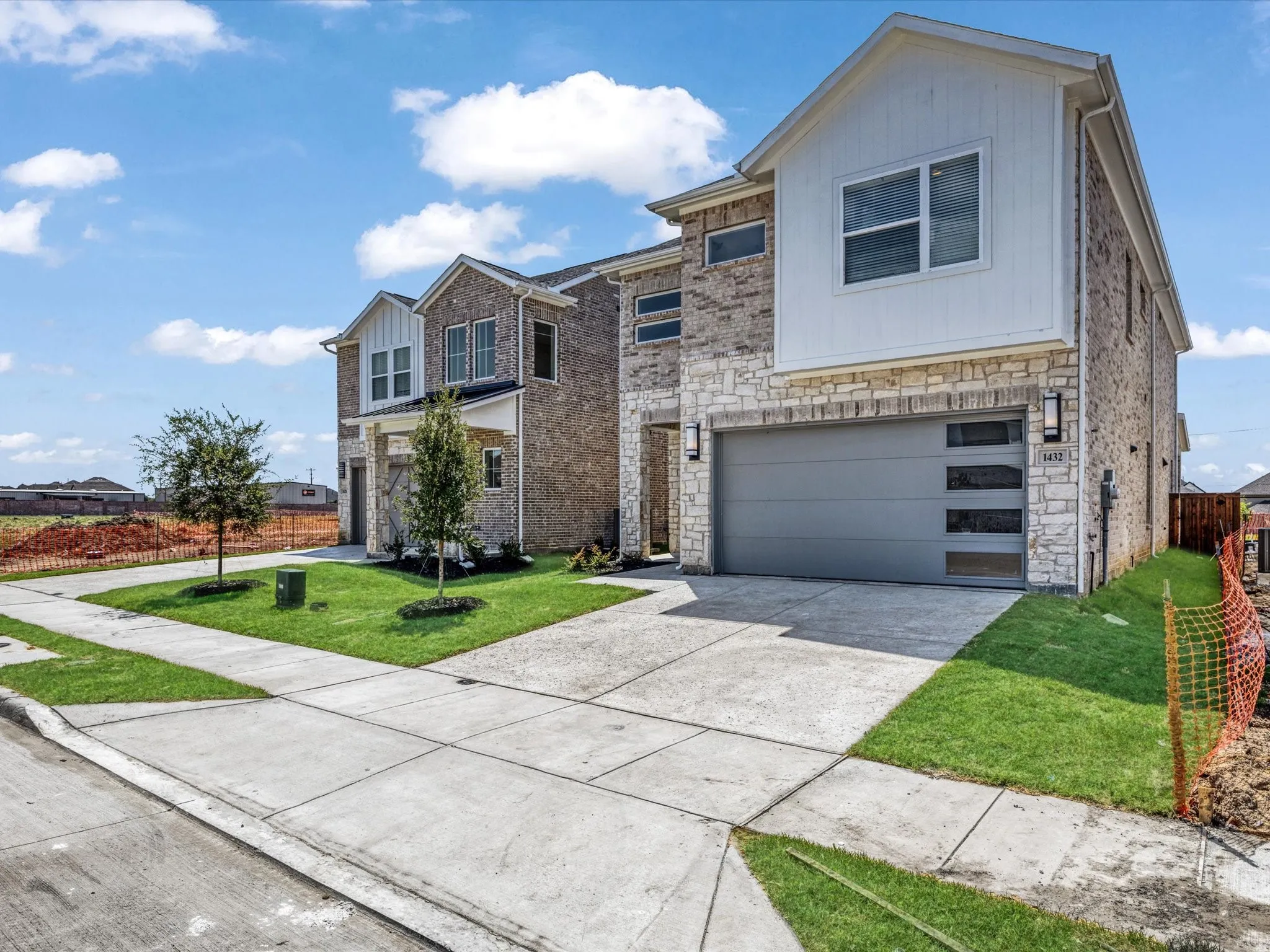 View of front of house with a front lawn, stone siding, concrete driveway, and an attached garage