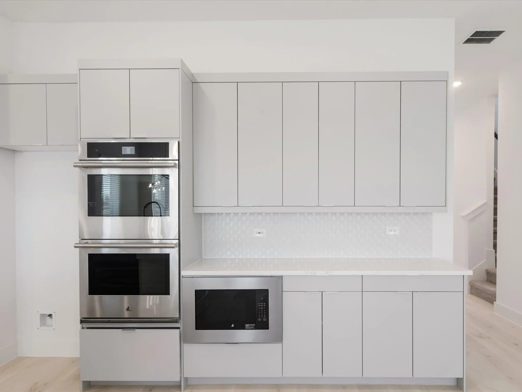 Kitchen with appliances with stainless steel finishes, modern cabinets, light wood-style floors, white cabinetry, and recessed lighting