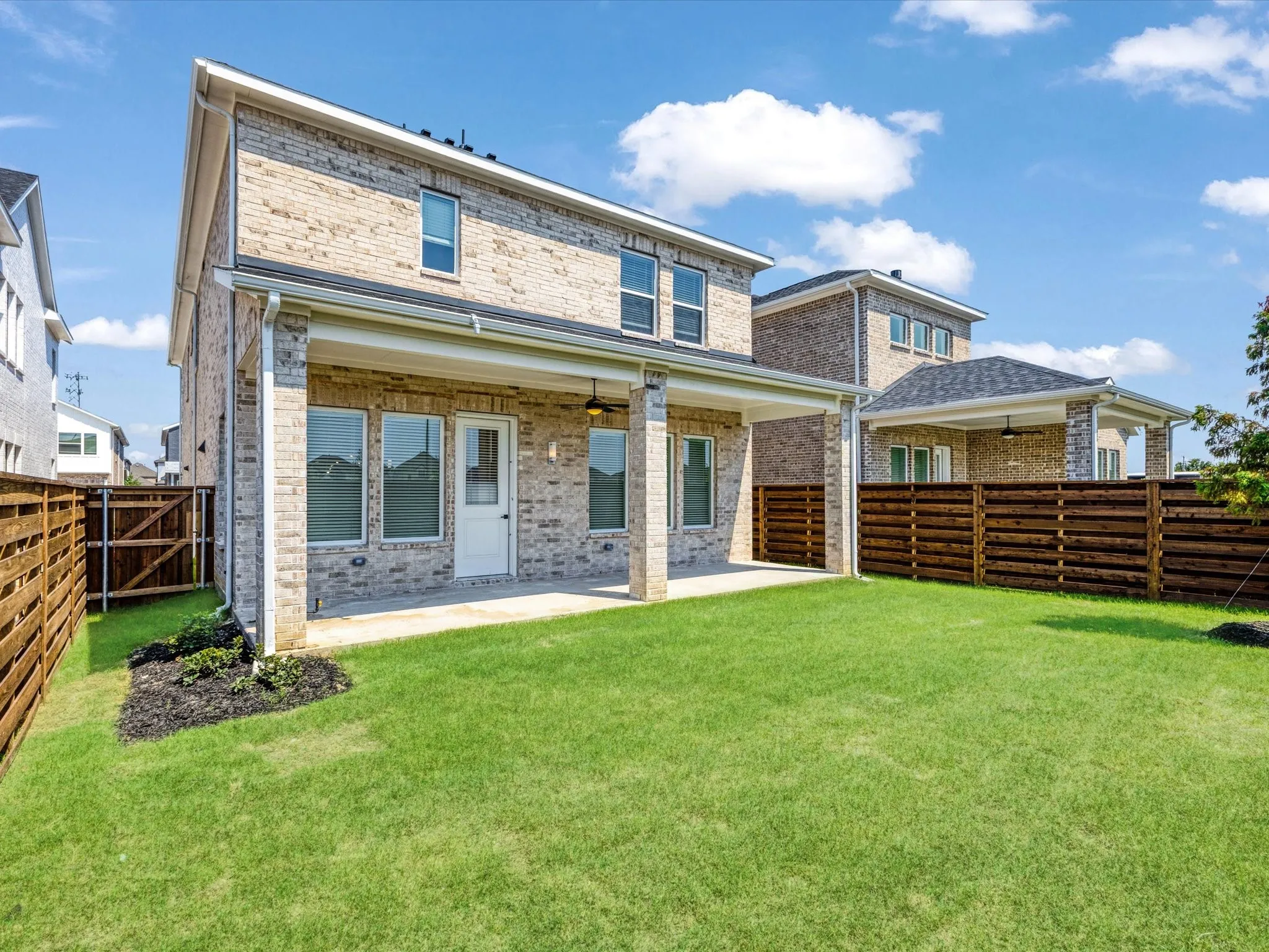 Back of property featuring brick siding, a patio, a ceiling fan, and a fenced backyard