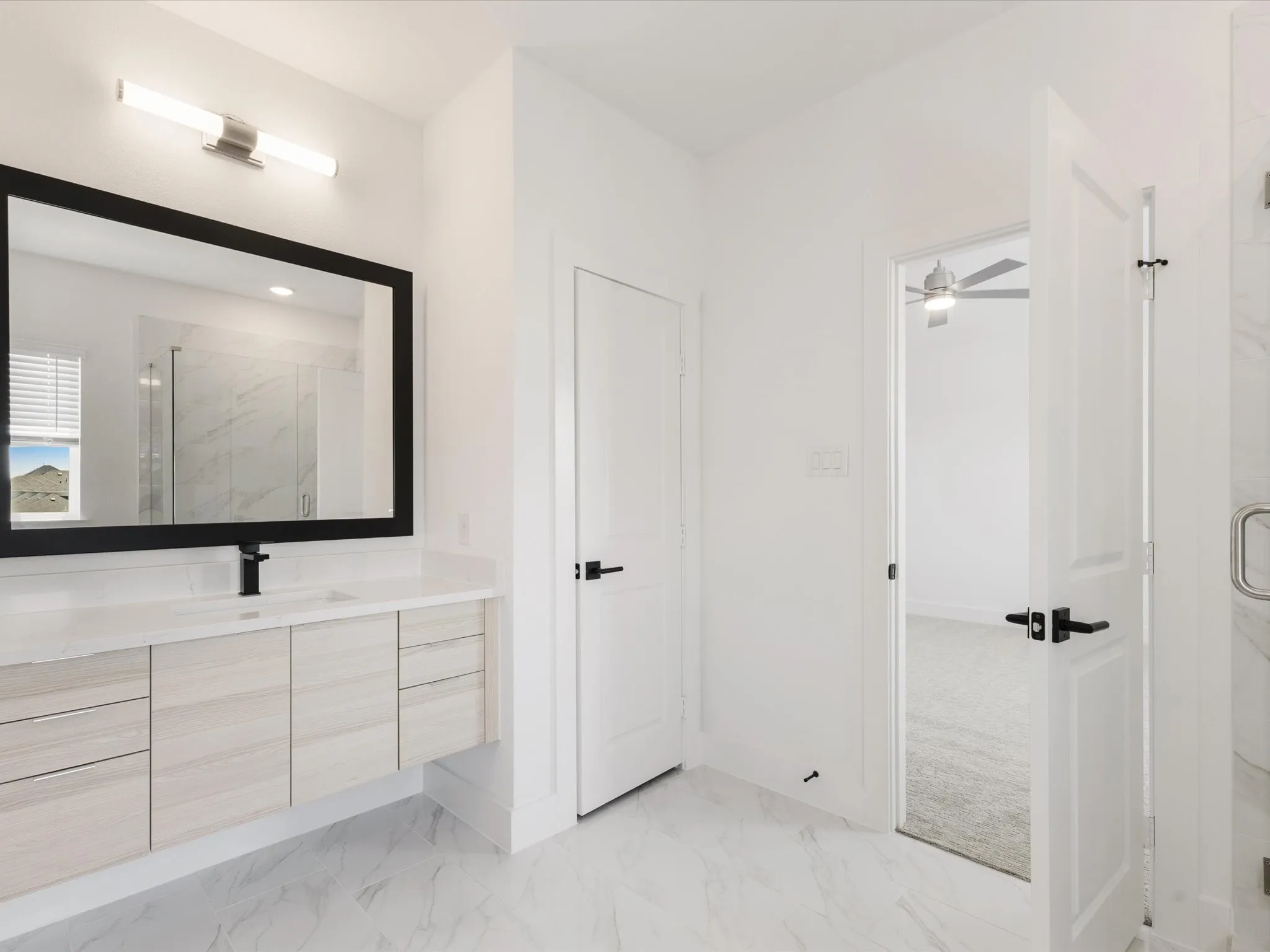 Ensuite primary bathroom with vanity, a marble finish shower, and light marble finish flooring