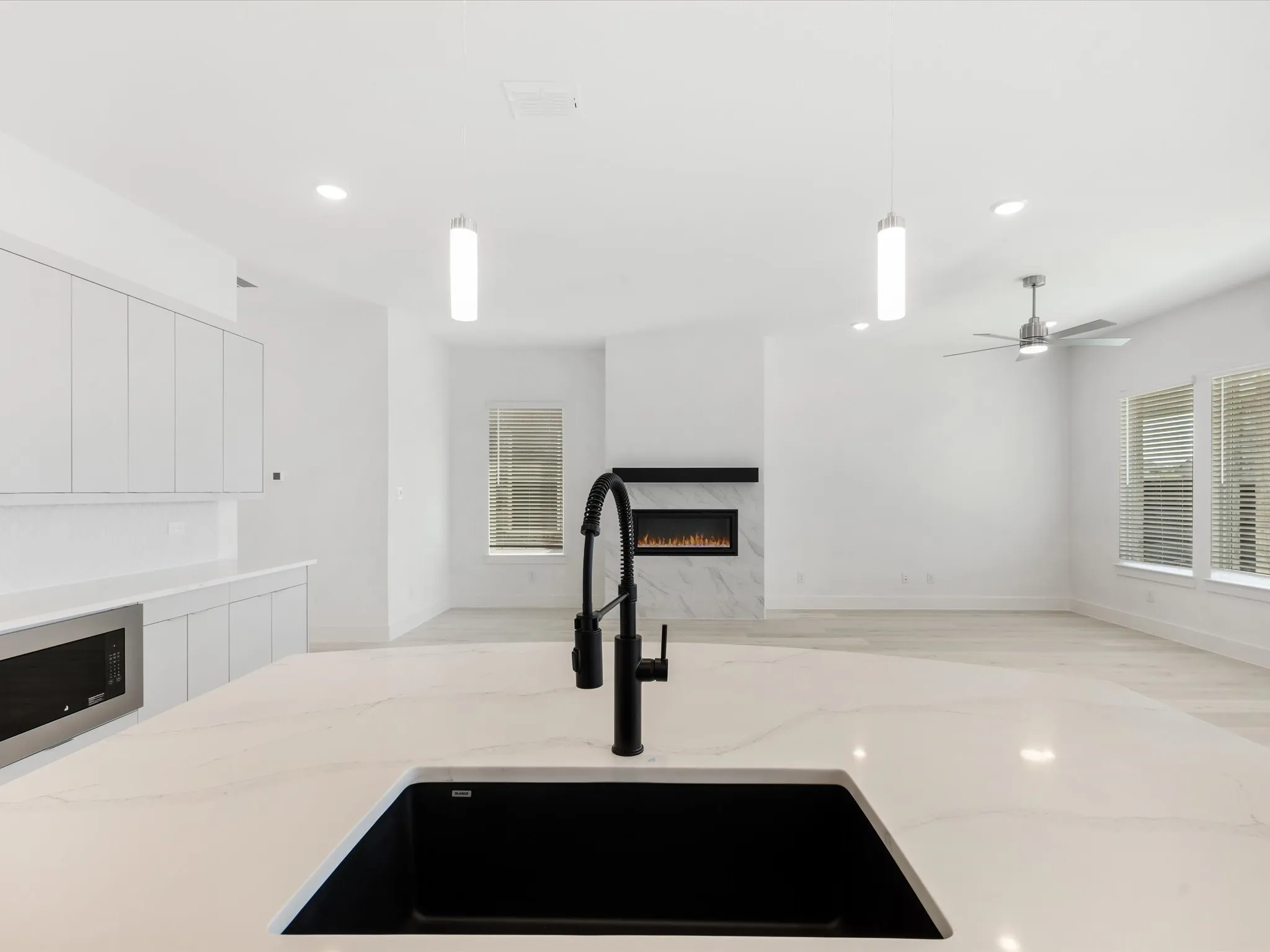 Kitchen featuring decorative light fixtures, recessed lighting, white cabinetry, and a premium fireplace
