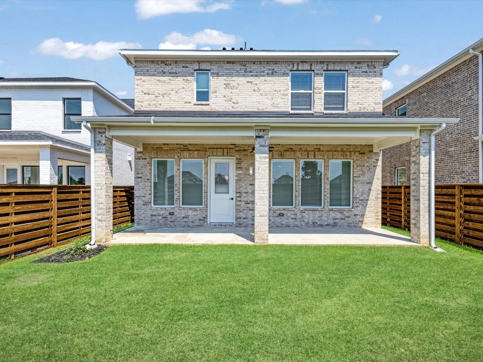 Back of property featuring brick siding, a fenced backyard, and a patio area