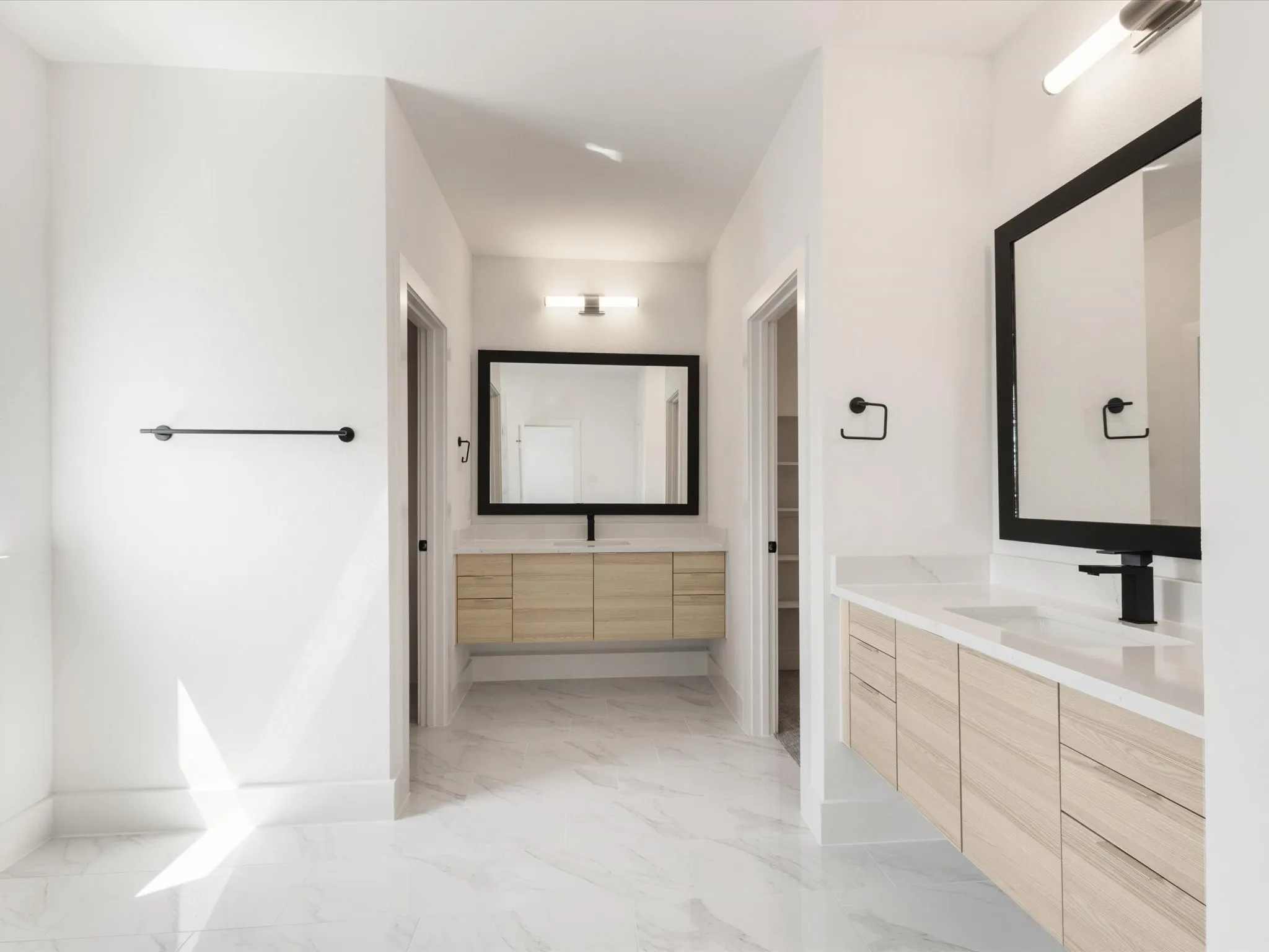 Ensuite primary bathroom with vanity, light marble finish flooring, and two sinks
