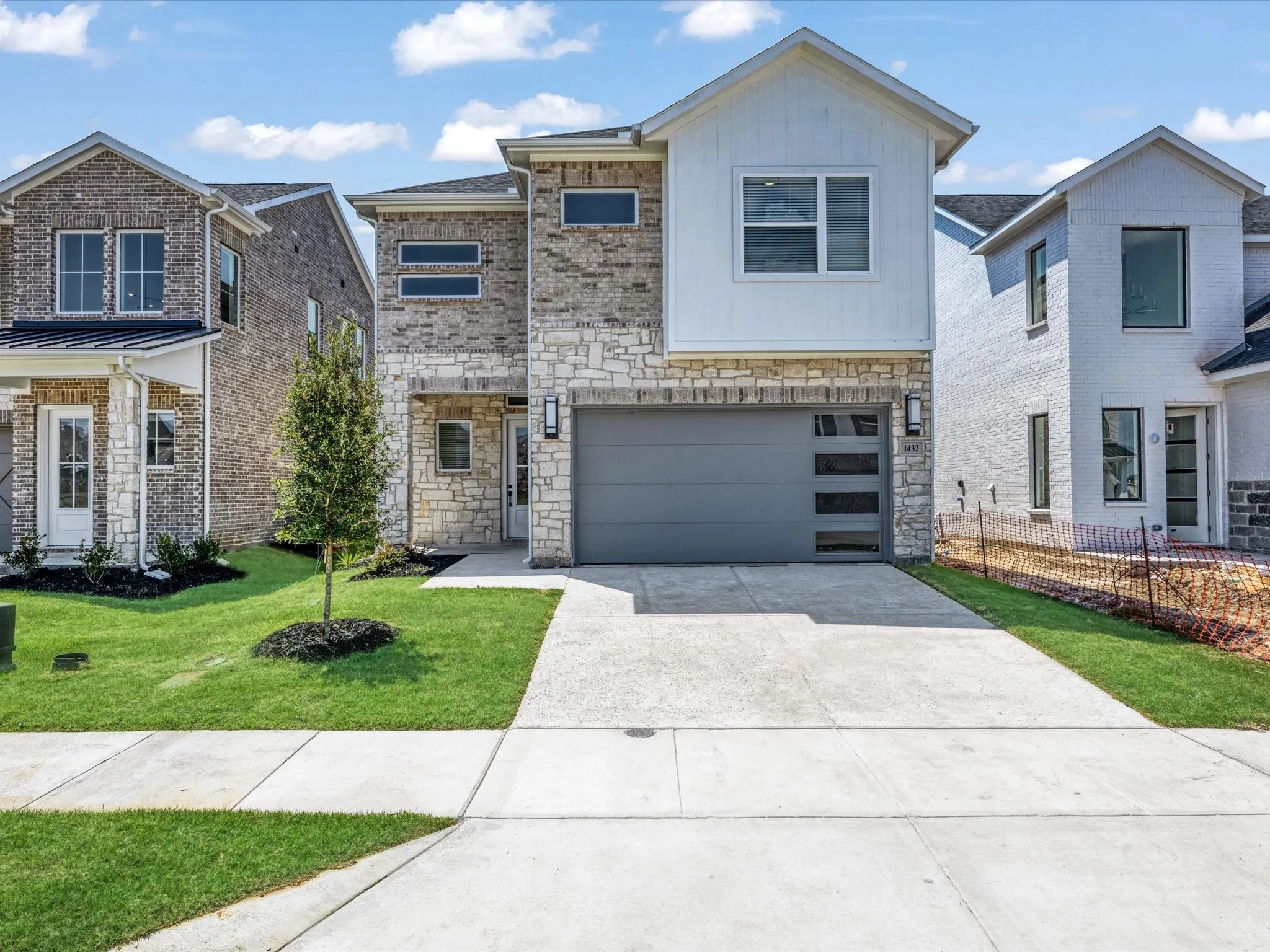 View of front of property featuring concrete driveway, stone siding, a garage, and a front yard