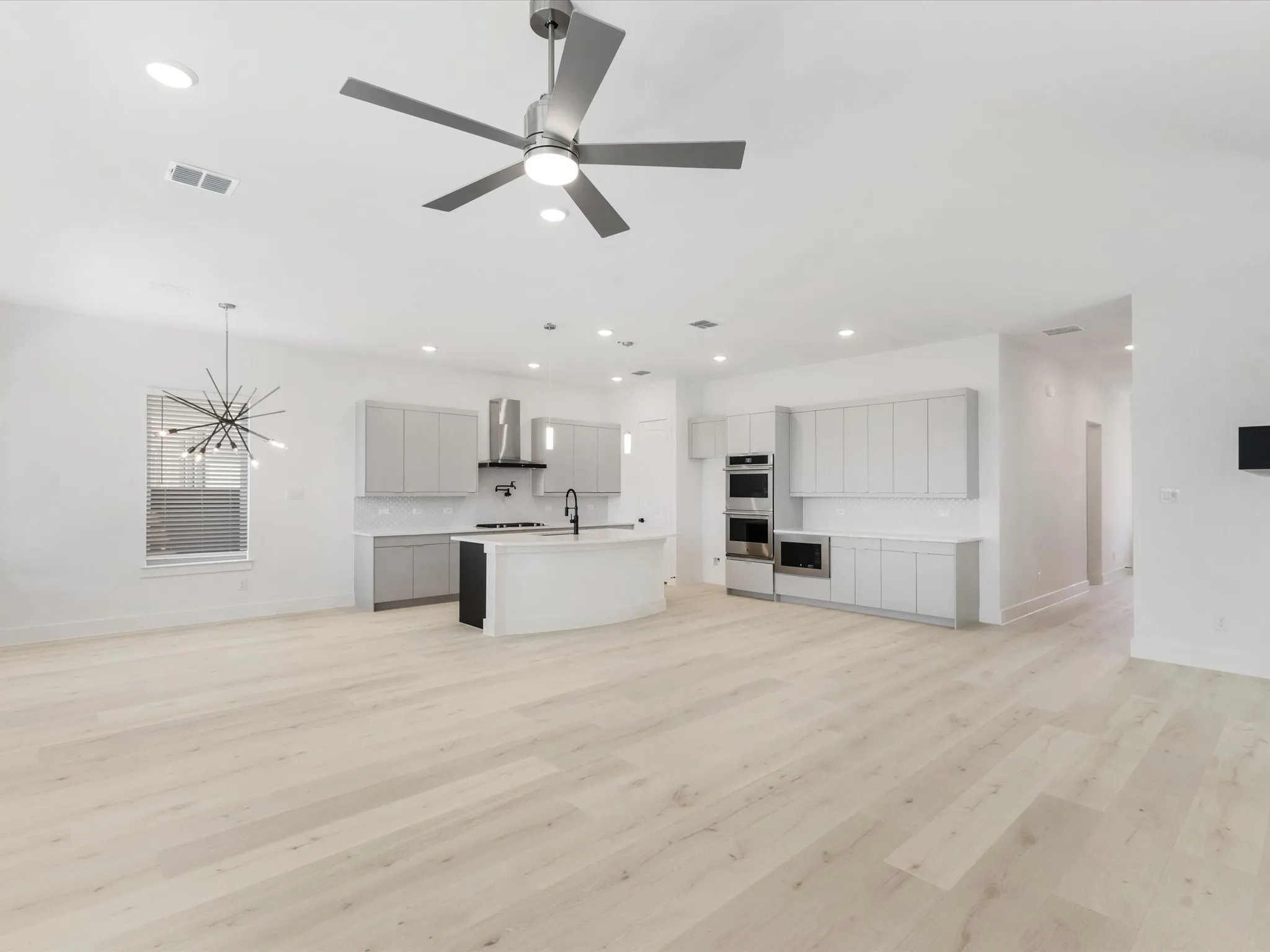 Spacious Living room featuring light wood-style floors, a chandelier, recessed lighting, and a ceiling fan