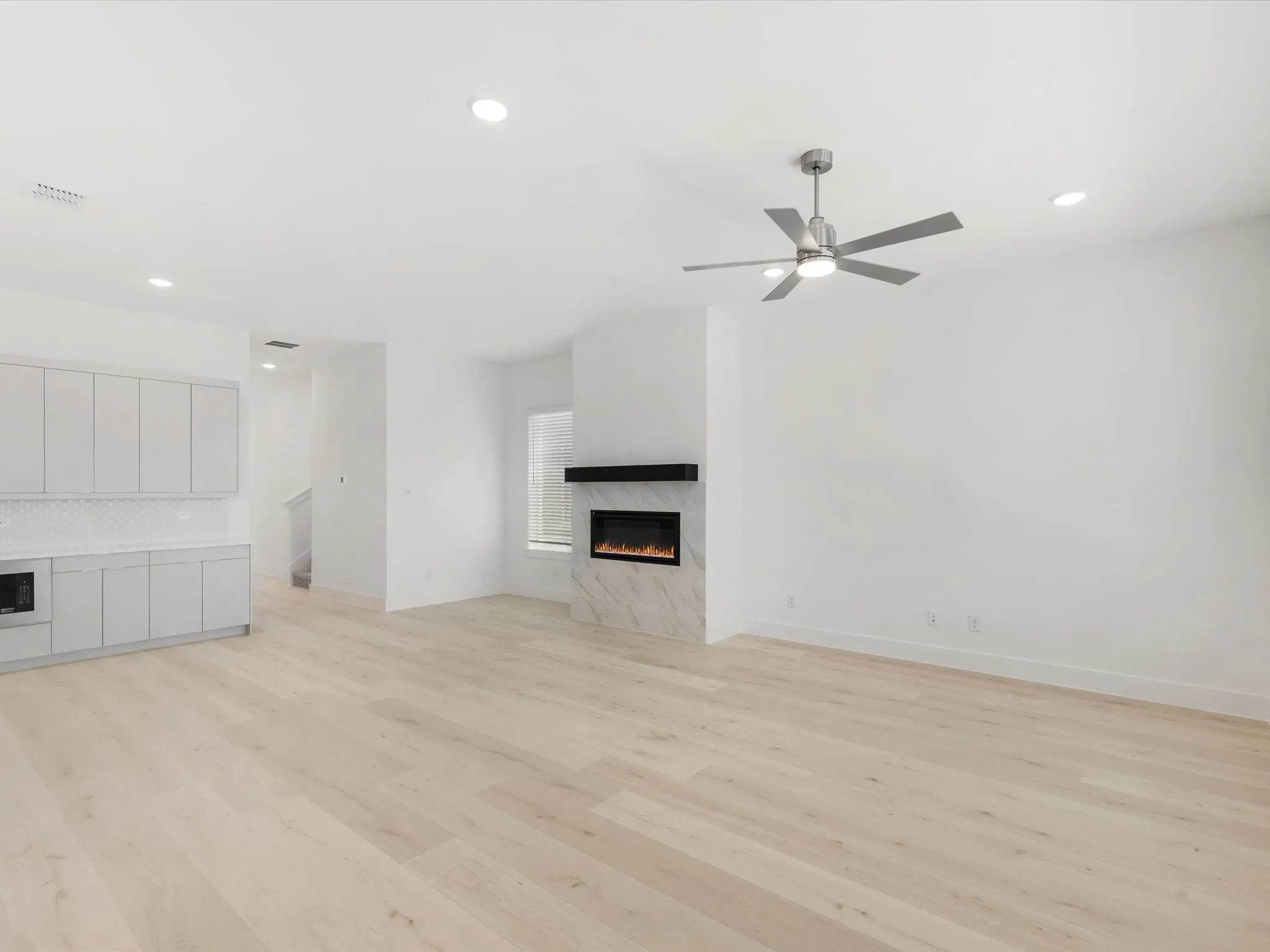 Living room with gas fireplace, recessed lighting, light wood-style floors, and ceiling fan