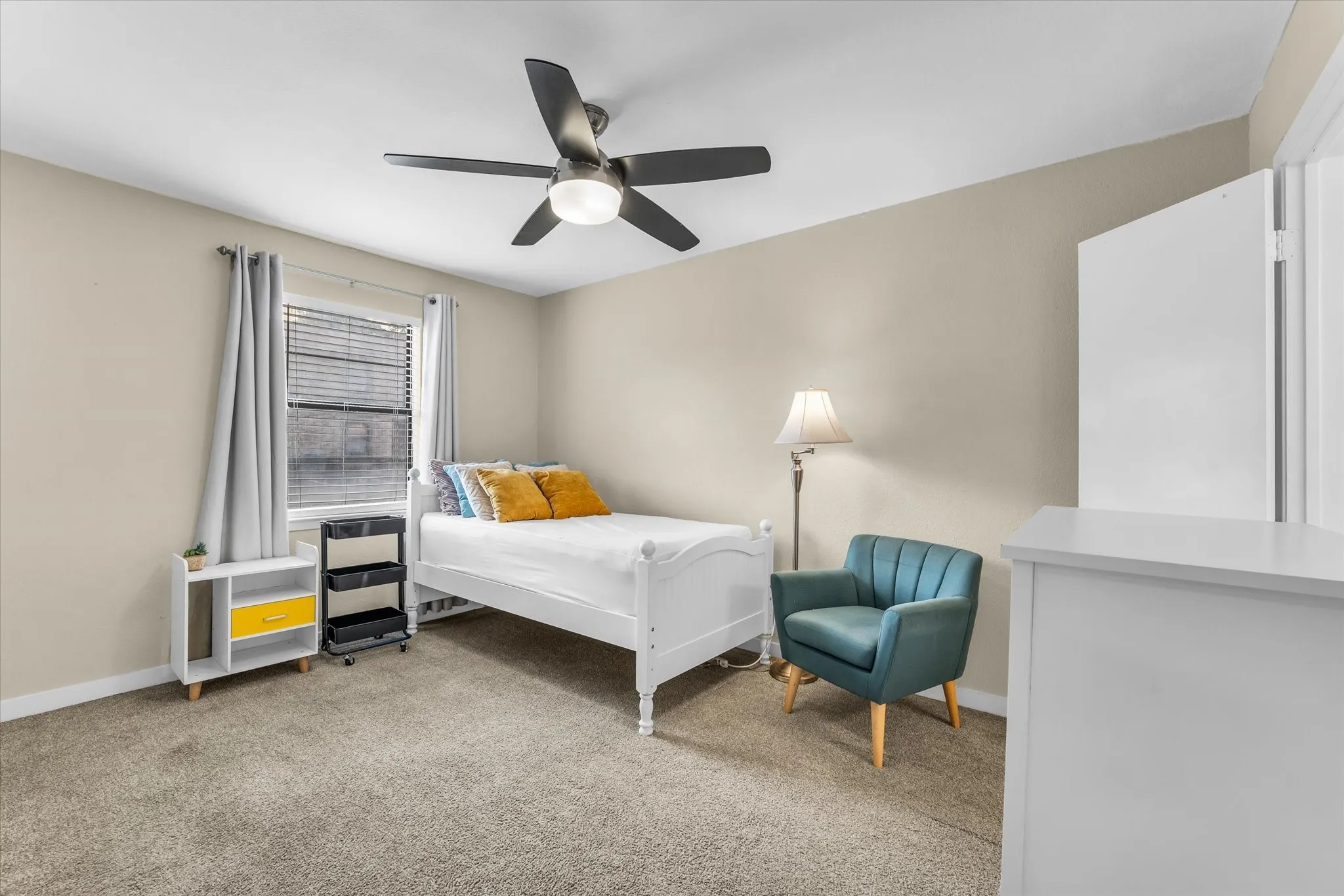 Carpeted room featuring a ceiling fan with integrated lighting, a window with blinds, and neutral-toned walls