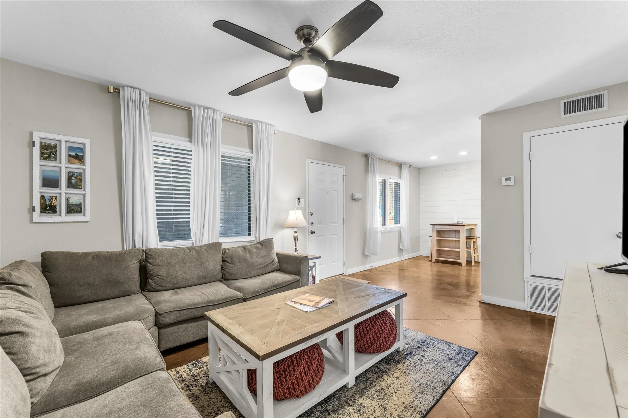Recessed lighting and a ceiling fan with integrated lighting illuminate the living space