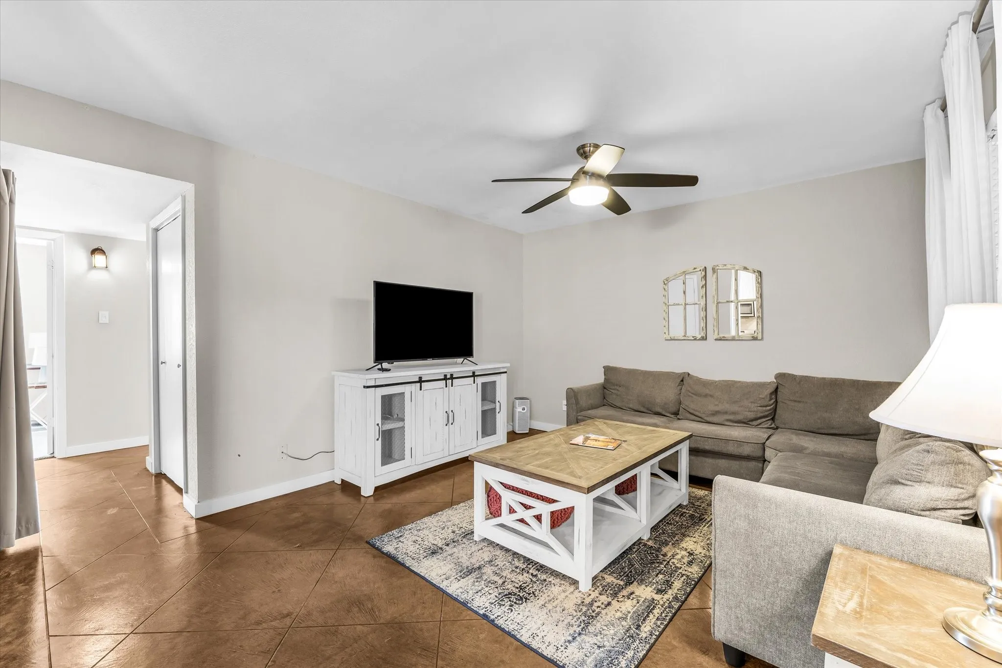 Spacious living area featuring tile flooring, a ceiling fan with integrated lighting, and neutral wall tones