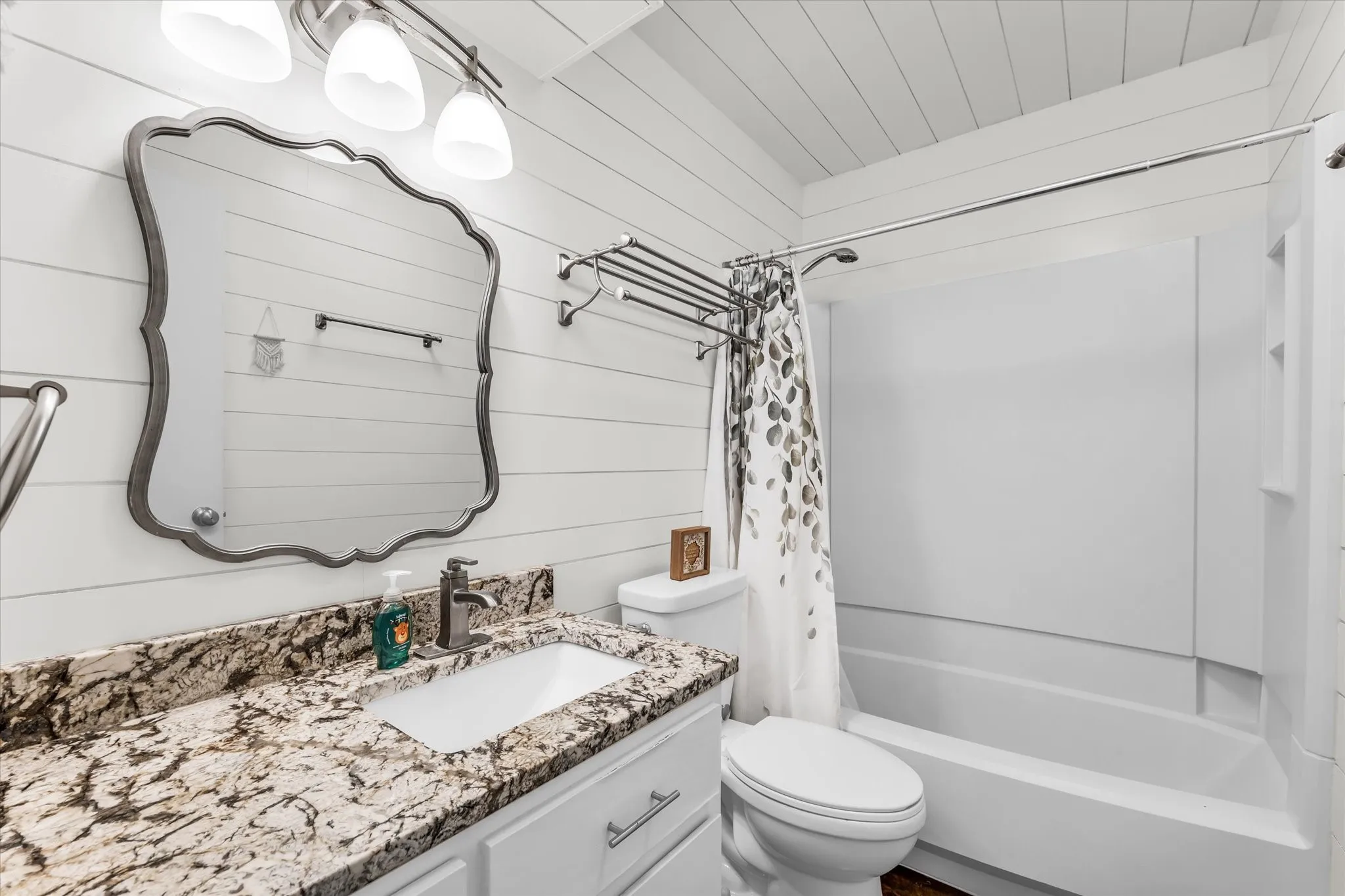 Bathroom featuring a white vanity with a rectangular sink, speckled countertop, and a shower-tub combination