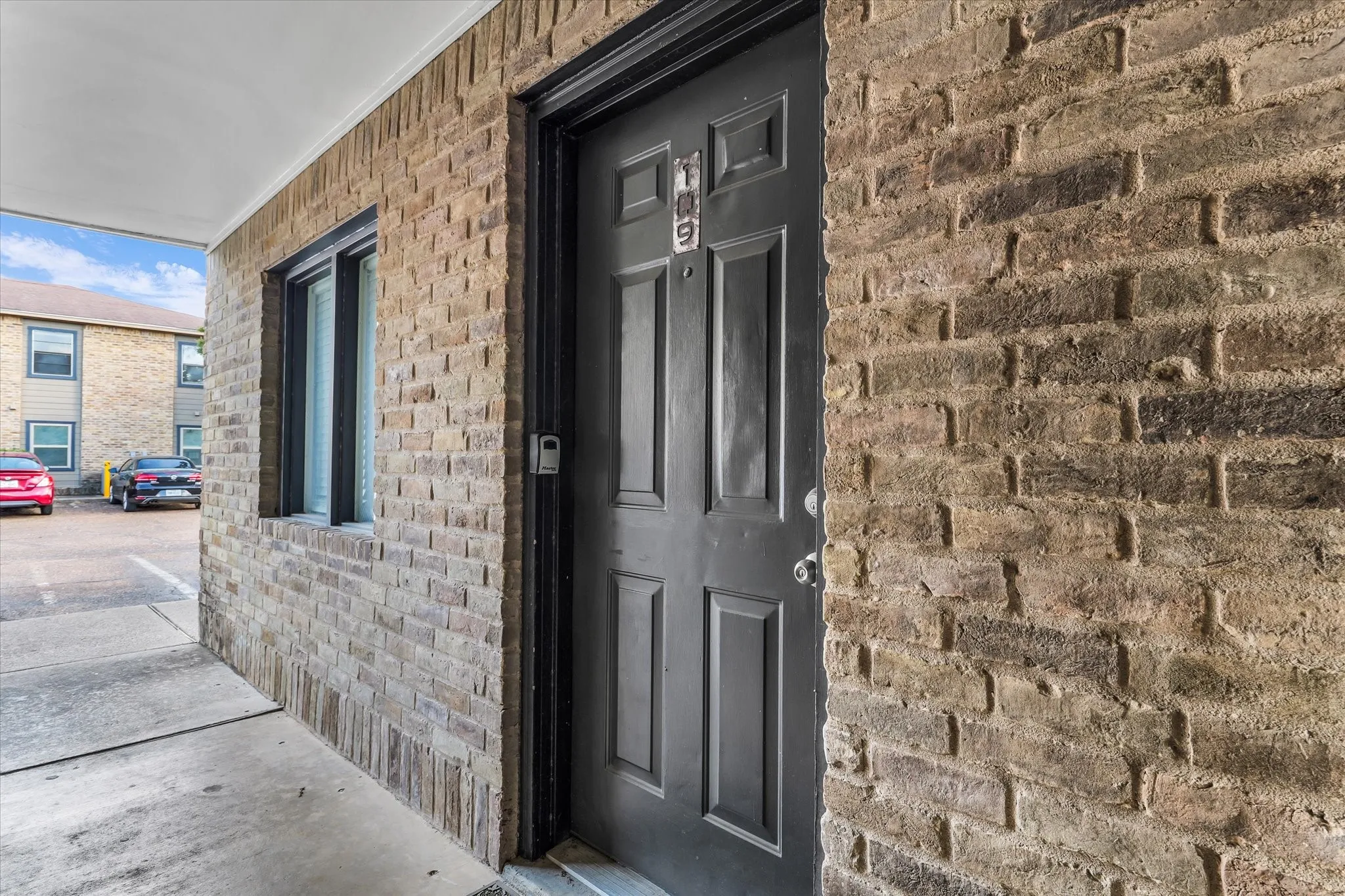 Brick exterior facade with an integrated window, covered entryway, and panel door