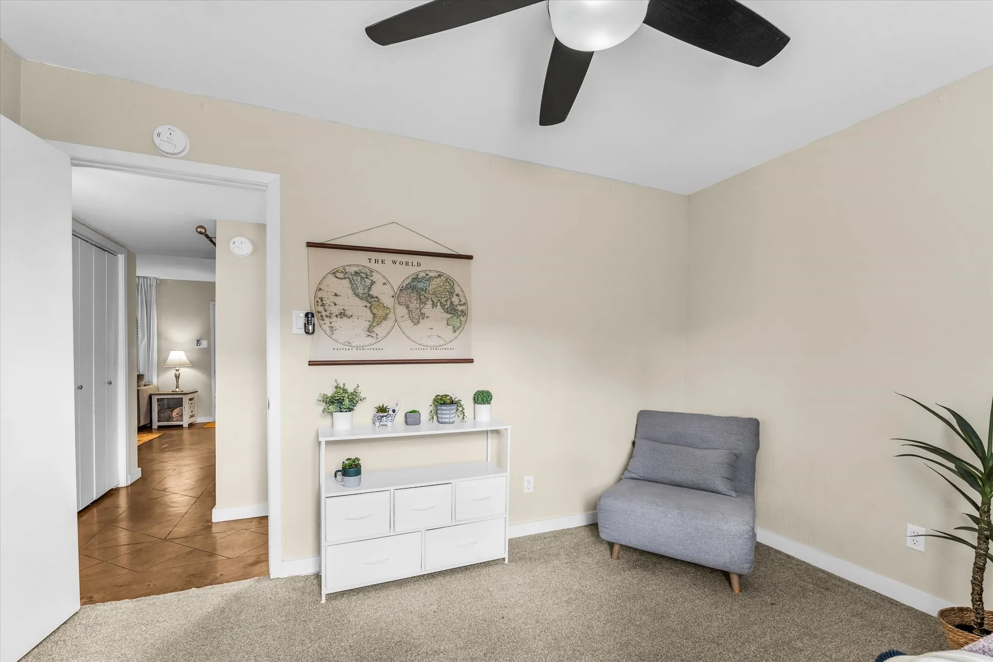 Carpeted room with a ceiling fan, light-toned walls, and white trim