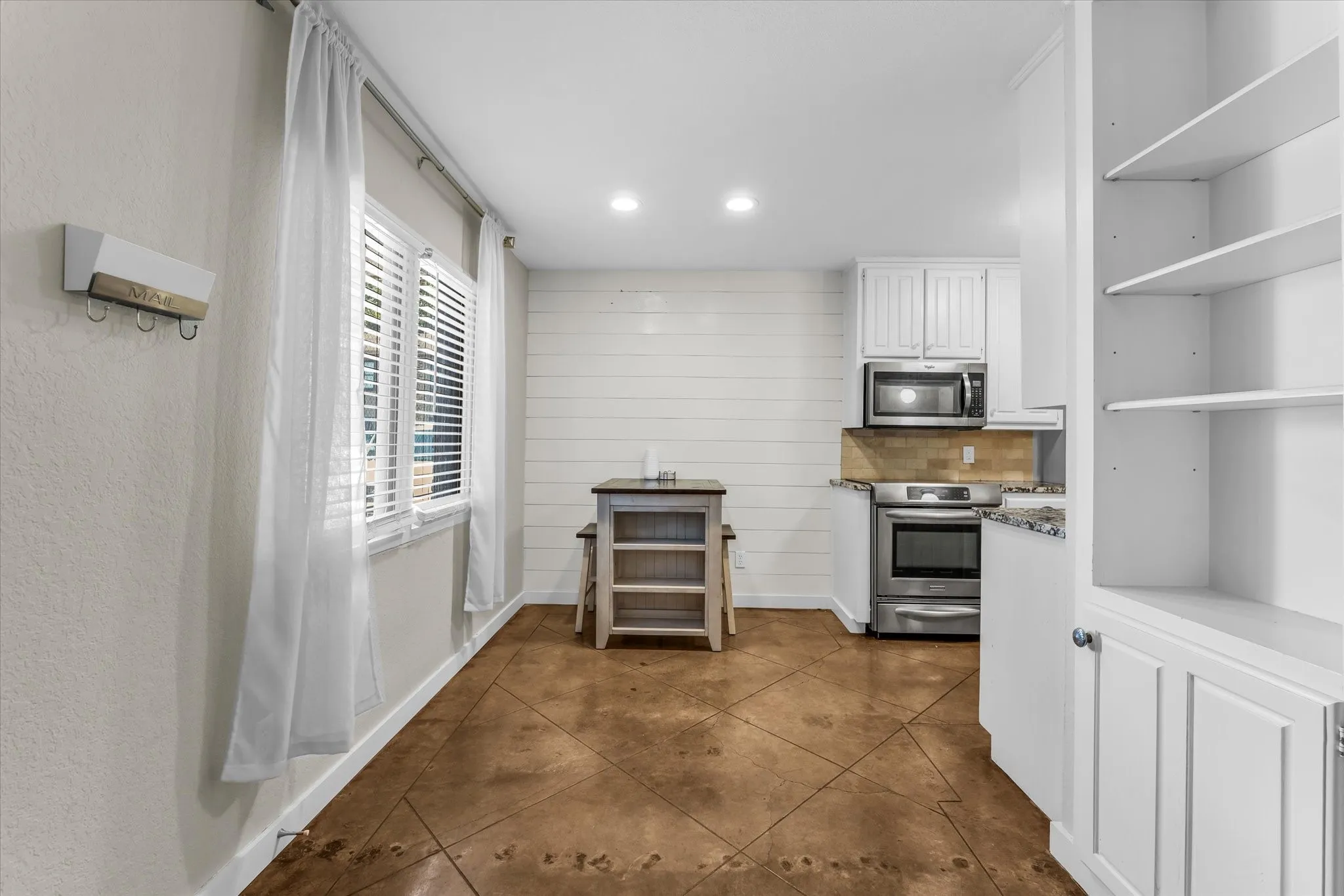 Kitchenette featuring stainless steel appliances, white cabinetry, and a subway tile backsplash