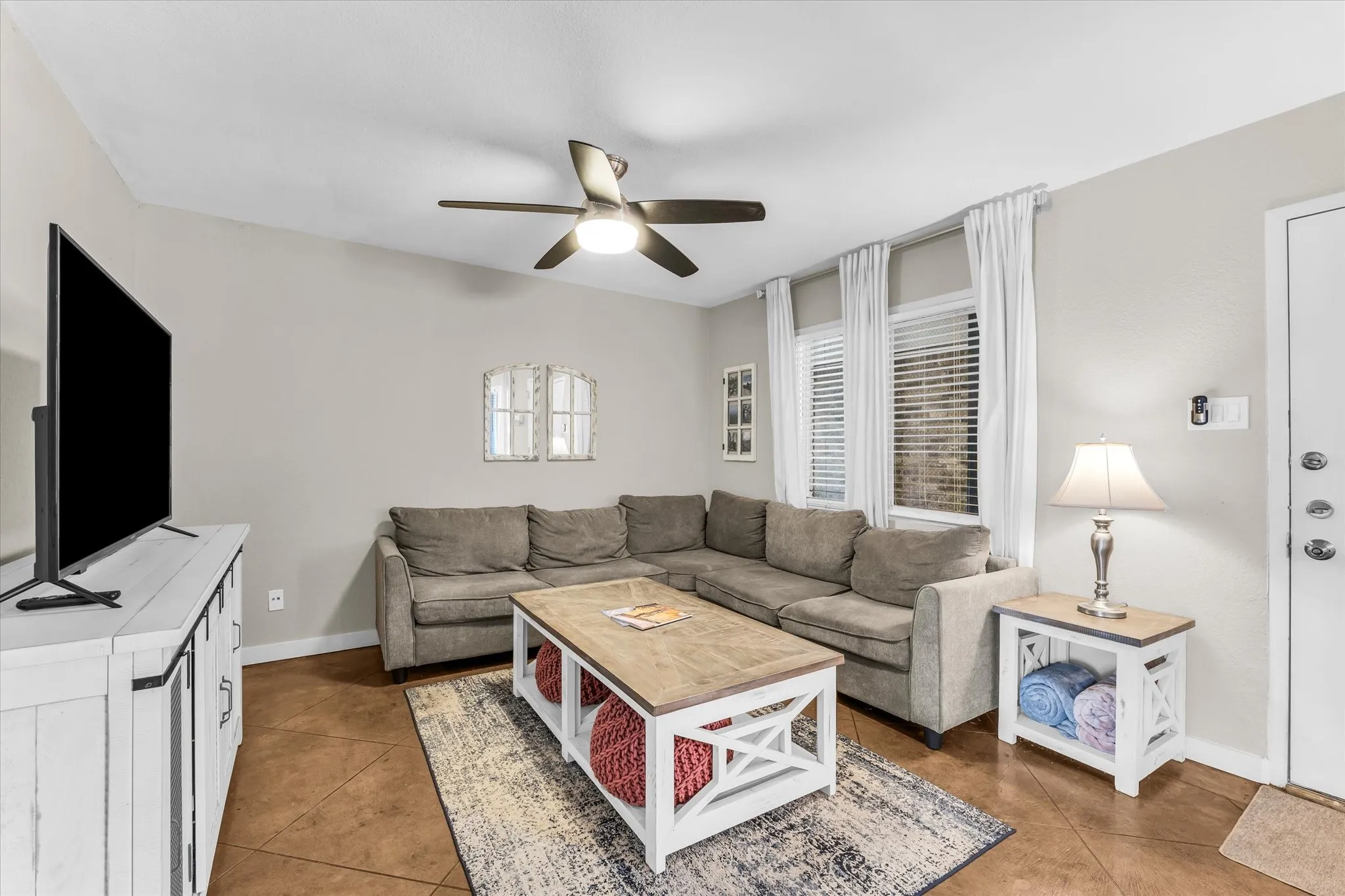 Vaulted ceiling with a ceiling fan, multiple windows with blinds, and durable flooring throughout