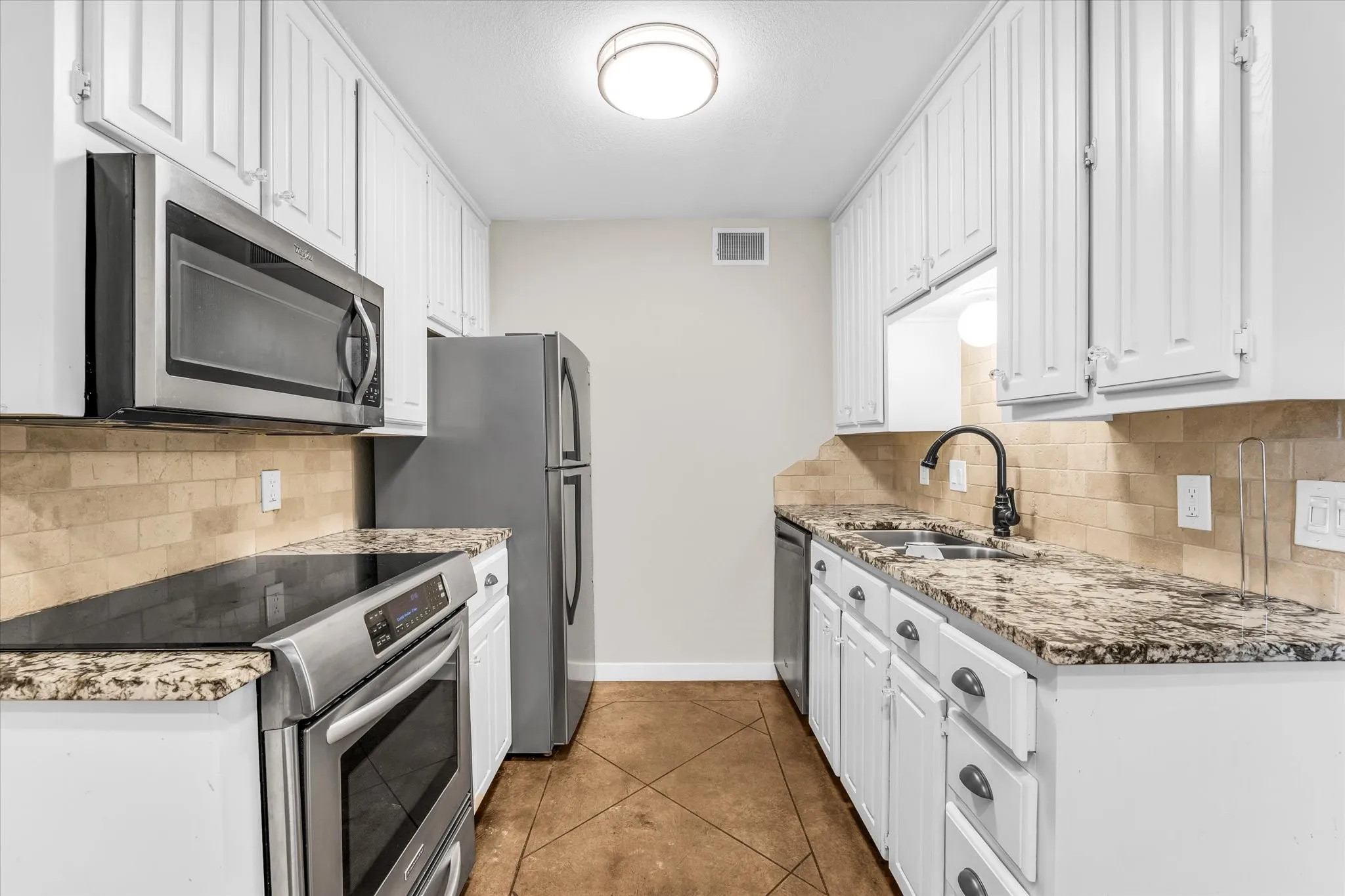 White cabinetry, stainless steel appliances, granite-look countertops, tiled backsplash, and a matte black faucet