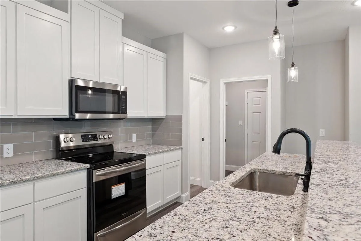 Kitchen with white shaker cabinetry, stainless steel appliances, speckled countertops, and a subway tile backsplash