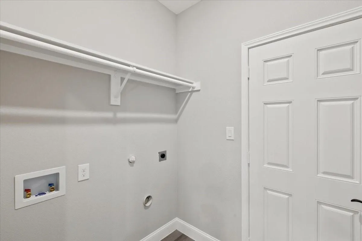 Dedicated laundry area featuring a built-in hanging rod, wall-mounted electrical outlets, and plumbing hookups