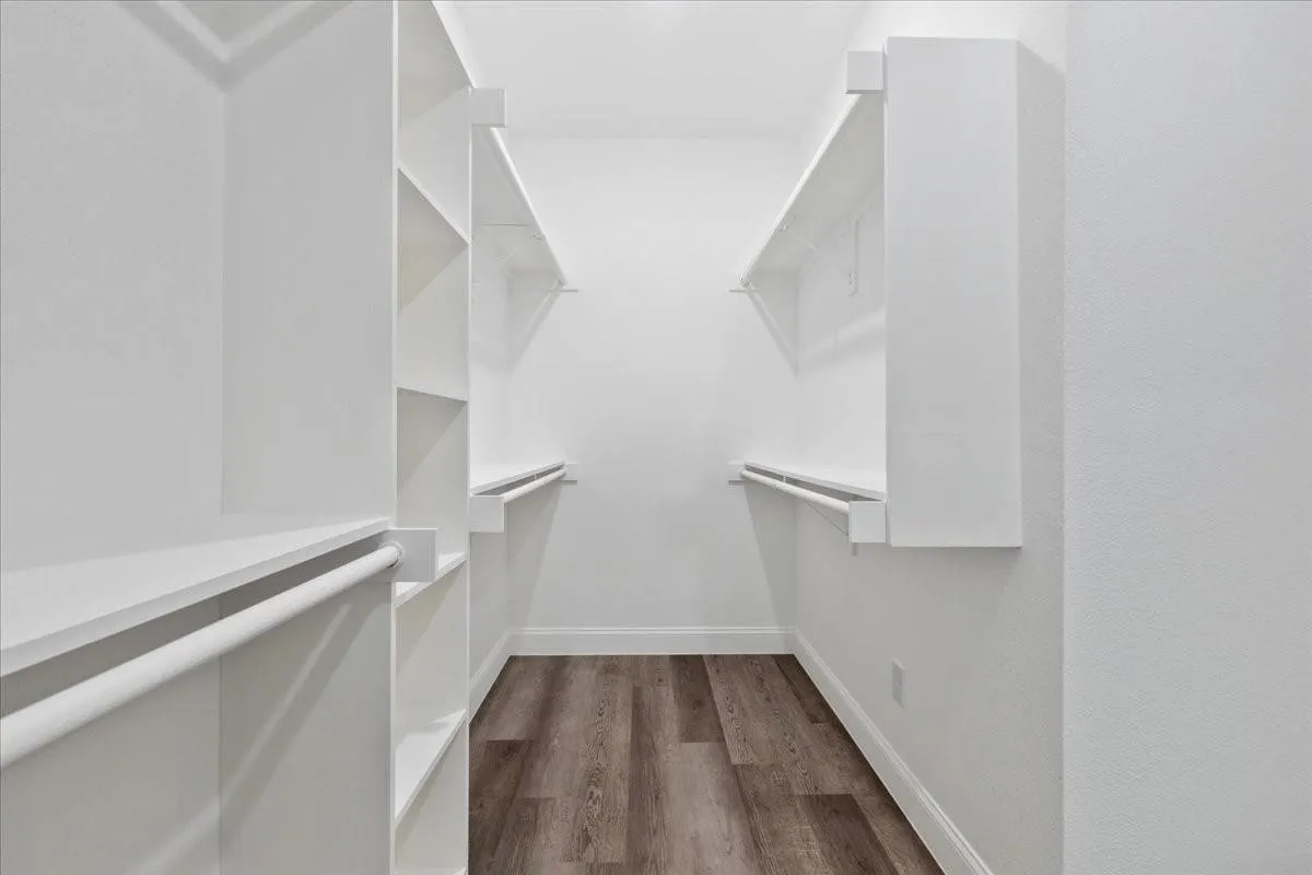 Walk-in closet with integrated shelving, hanging rods, and wood-finish flooring