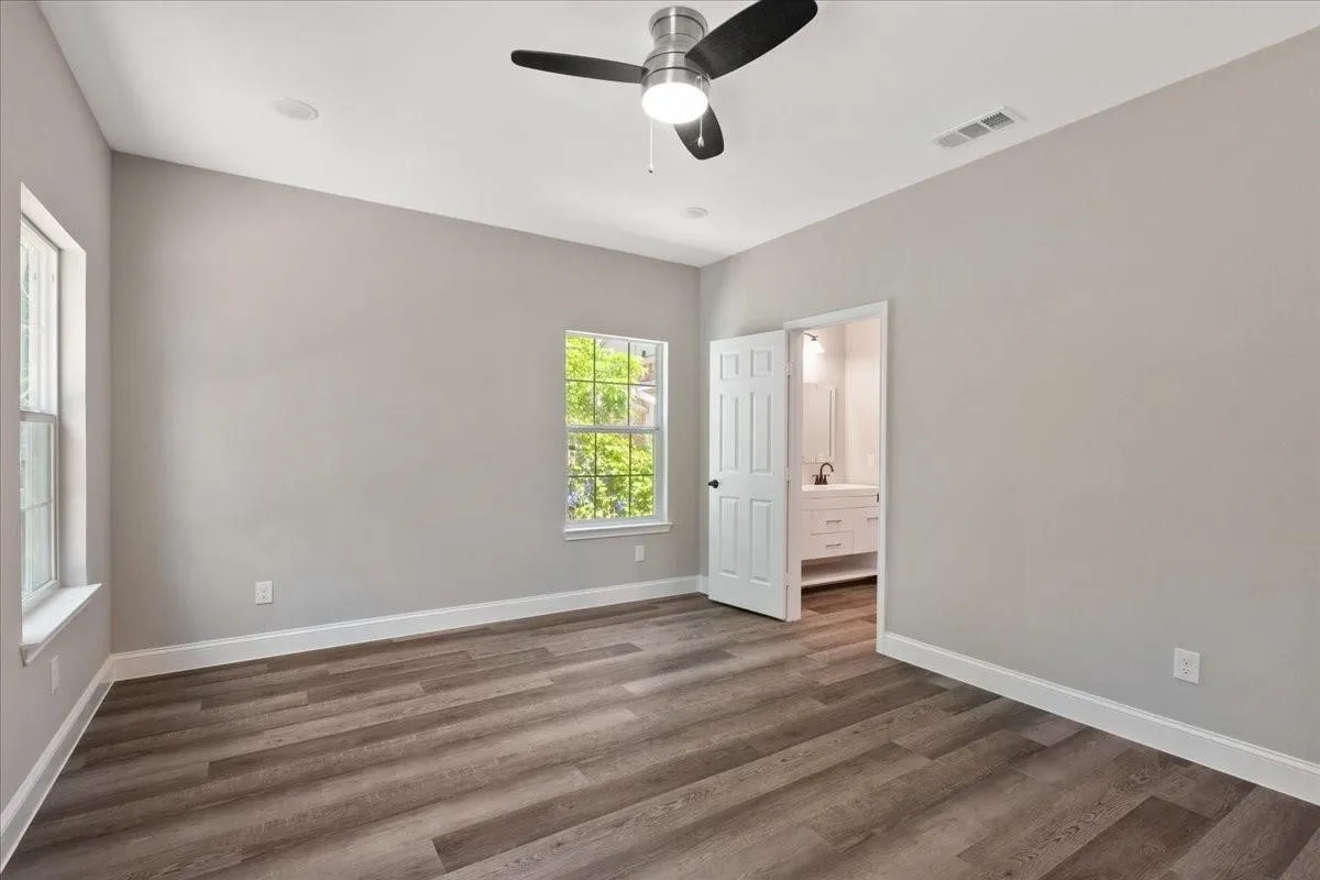 Wood-finish flooring, two windows, ceiling fan, recessed lighting, and a white interior door