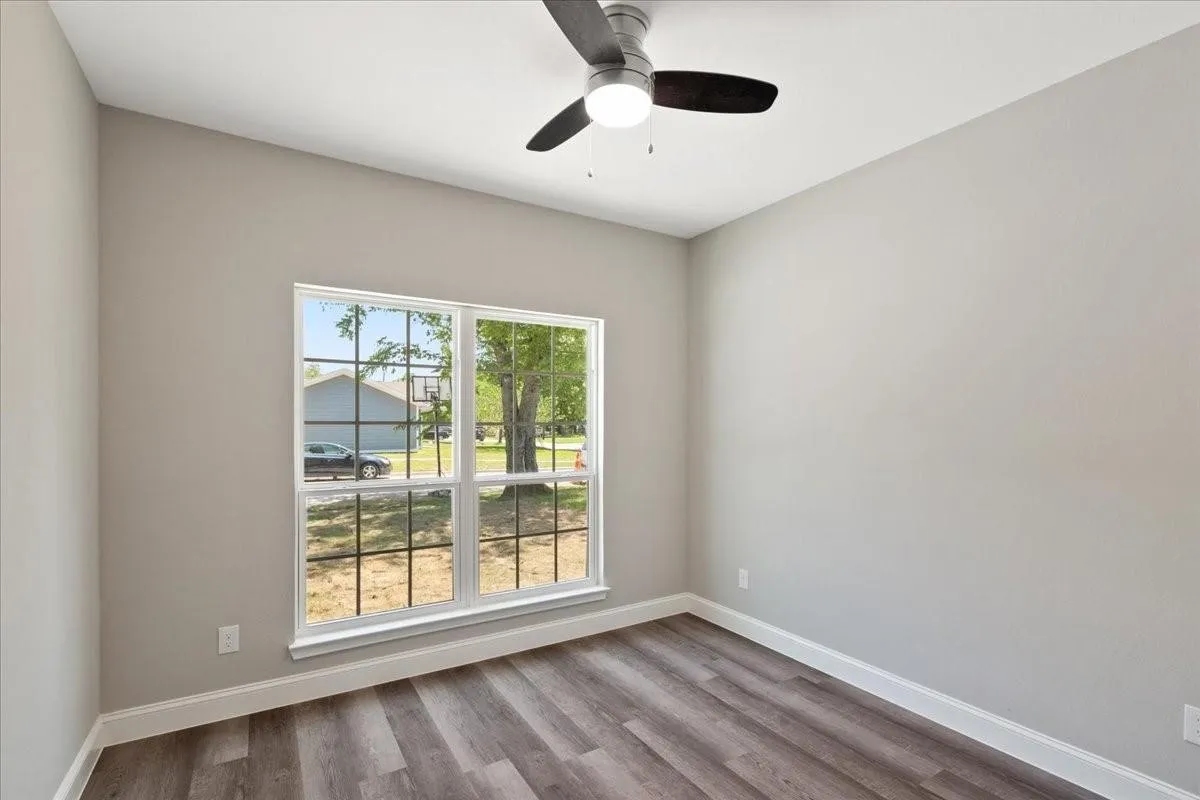 Vaulted ceiling with a ceiling fan, wood-finish flooring, and a multi-pane window