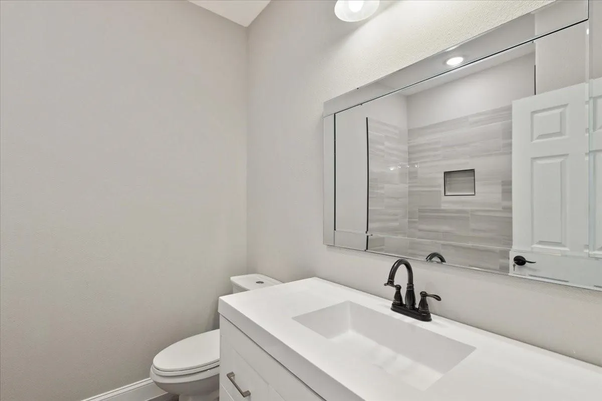Vanity featuring a rectangular undermount sink, dark bronze-finish faucet, and a large wall-mounted mirror